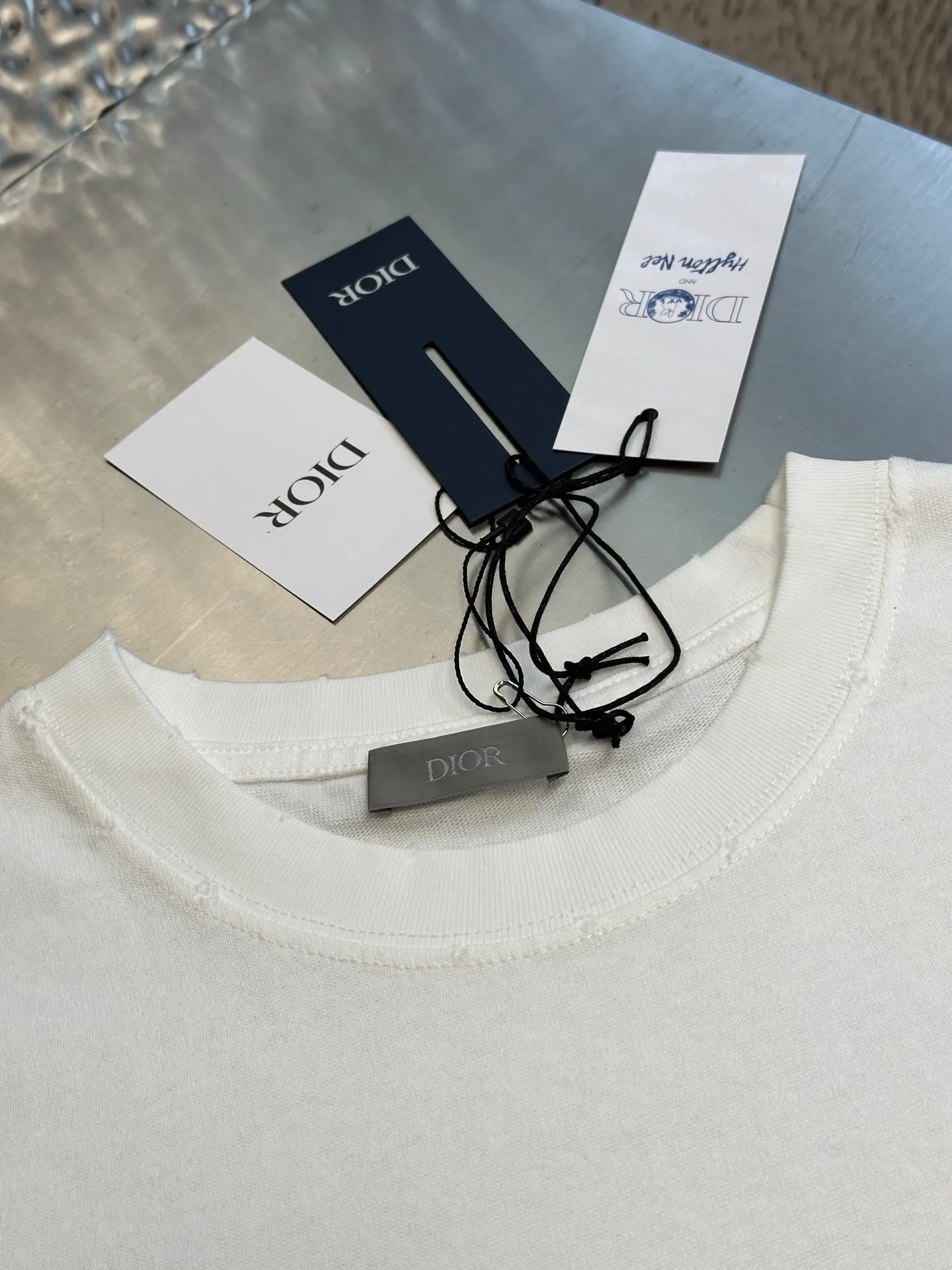 🅿️280 Dior Friends letter embroidered round neck short sleeves are made of pure cotton 12S fine cotton plain weave. The fabric is interwoven with plain weave. The yarns have many buckling points, which makes the fabric have good fastness and wear resistance. The density is moderate, the fabric is thin, flat and stiff. It has good breathability, is softer, more delicate, and has better gloss.  The joint series logo is chain embroidery. Chain embroidery is named because the visual effect of the embroidery is like a chain. The shape is like the links on the chain. It is commonly known as chain embroidery and also called chain eye embroidery. Follow the chain stitch stitch method and embroider from right to left. Maintain the tension of the embroidery thread and the uniformity of the stitches to ensure the three-dimensionality and exquisiteness of the embroidery. It combines the stitching method of chain embroidery with the material of fine wool to create embroidery with chain-like texture and three-dimensional effect.  The whole piece is designed with washed holes and irregular openings all over the body. The simple garments have a rebellious and destructive design. The stone grinding washing process locates the holes, and the ready-to-wear products use the stone grinding machine laser positioning to manually destroy the wear effect. Every wear and tear is made by hand, so that the natural wear and tear of the fabric achieves the most harmonious visual effect. After being washed by stone grinding, it can show a rich retro atmosphere.  The standard round neck and short-sleeved version has a rounded arc neckline, which is suitable for various face shapes and body shapes; the sleeve length is moderate and ends just above the elbow, showing a smart and neat image. The slim fit can show off the wearer's body curves without sacrificing comfort. The collar, cuffs, hem and other parts are all sewn with fine double-needle stitching.  size：xs s m l