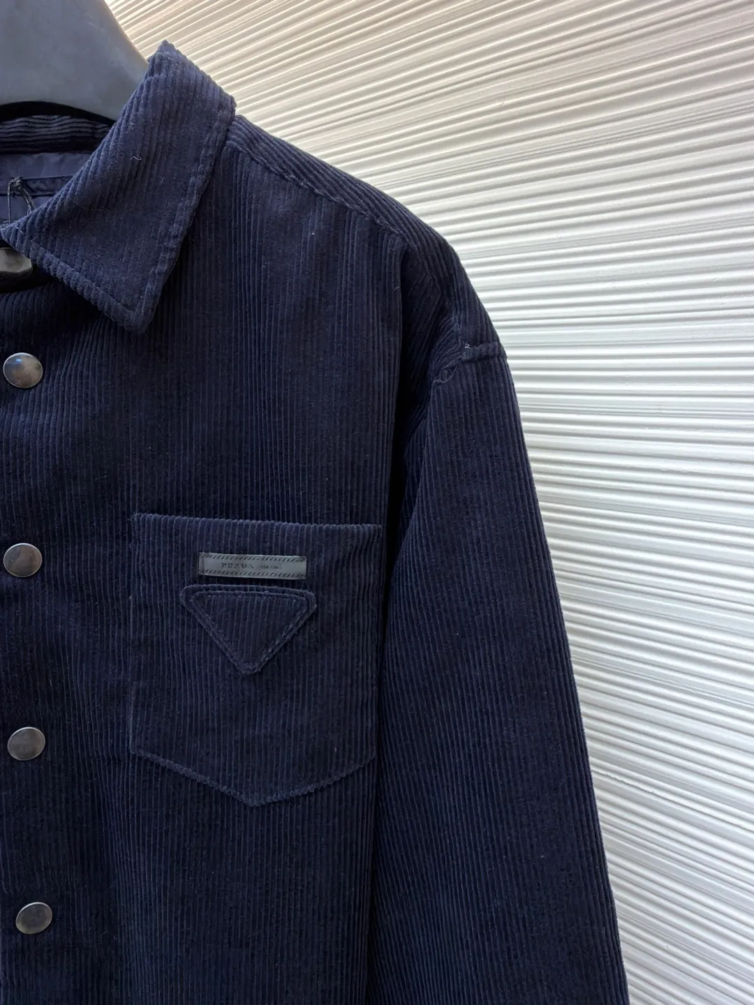 Prada pocket triangle logo corduroy cotton jacket ●Original version: Purchased and developed for 16999 ●Item number: 1681386-B80 ●Fabric: corduroy fabric ●Technology: made on positioning cutting machine ●Color: navy ●Version: fitted version ●Weight: about 820 grams ●Size: S-M-L-XL ●Description: This item is made of high-quality corduroy fabric, and the main tone of dark blue presents a retro texture. It has a lapel design and a metal button placket, which is classic and tool-style. The single patch pocket on the front chest is decorated with the brand's iconic triangle logo, which presents a three-dimensional structure through precision sewing; the corduroy fabric has been specially washed to give it a soft and aged texture, with a soft touch and clear texture. In terms of sewing process, the seams are neatly and firmly routed, and the buttons are made of high-quality metal material, which is durable. From fabric washing to detail decoration, every process pays attention to the presentation of retro style, integrating workwear elements with retro corduroy technology to present a single product that is both practical and stylish. The overall wiring is straight and delicate, the fabric is comfortable and soft, and the color is consistent without color difference. It can be matched with the same style to create a fashionable look and control various occasions. Customized accessories, complete with three standards, same style for men and women!