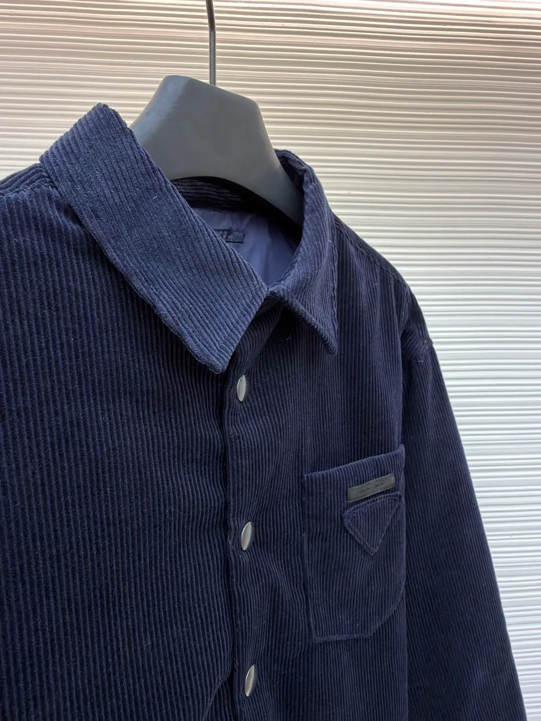 Prada pocket triangle logo corduroy cotton jacket ●Original version: Purchased and developed for 16999 ●Item number: 1681386-B80 ●Fabric: corduroy fabric ●Technology: made on positioning cutting machine ●Color: navy ●Version: fitted version ●Weight: about 820 grams ●Size: S-M-L-XL ●Description: This item is made of high-quality corduroy fabric, and the main tone of dark blue presents a retro texture. It has a lapel design and a metal button placket, which is classic and tool-style. The single patch pocket on the front chest is decorated with the brand's iconic triangle logo, which presents a three-dimensional structure through precision sewing; the corduroy fabric has been specially washed to give it a soft and aged texture, with a soft touch and clear texture. In terms of sewing process, the seams are neatly and firmly routed, and the buttons are made of high-quality metal material, which is durable. From fabric washing to detail decoration, every process pays attention to the presentation of retro style, integrating workwear elements with retro corduroy technology to present a single product that is both practical and stylish. The overall wiring is straight and delicate, the fabric is comfortable and soft, and the color is consistent without color difference. It can be matched with the same style to create a fashionable look and control various occasions. Customized accessories, complete with three standards, same style for men and women!