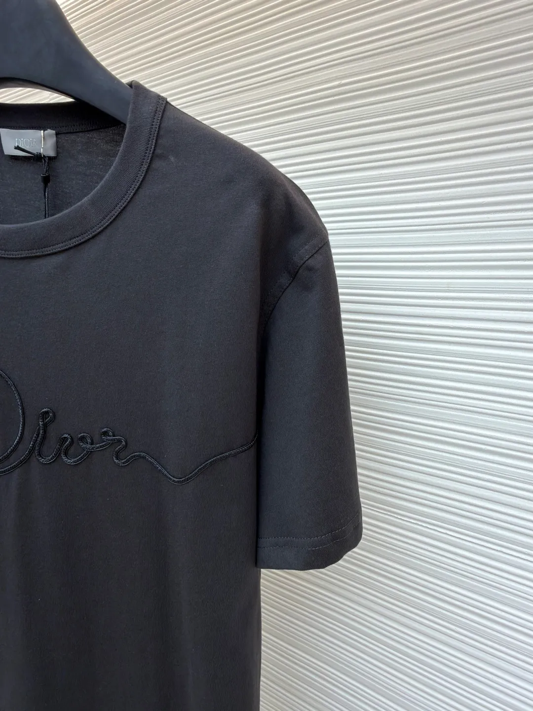 Dior satin emblem round neck short sleeves ●Original version: purchased and developed by 7089 ●Item number: 1681694-A00 ●Fabric: cotton jersey fabric ●Technology: embroidery production ●Color: dark gray ●Version: fitted version ●Weight: about 200 grams ●Size: XS-S-M-L ●Description: The main body is made of 24-count special-spun compact cotton. The weight of 185g/㎡ is light to medium, ensuring the lightness, breathability and good drape of the T-shirt. It is suitable for both spring wear alone and as an inner layer. With 32 pieces of 1×1 rib, 300g/㎡. Its special spinning and compacting process means that compact spinning technology is used in the spinning process, which effectively reduces the hairiness of the yarn, making the yarn smoother and stronger. The woven fabric therefore has the advantages of compact structure, smooth surface, and resistance to pilling. The final dark gray tone is combined with the simple texture of jersey to create a high-end matte texture. Embroidery decoration in the form of satin ribbons, which are fixed on the fabric through special processing. The texture brought by this process is usually different from the woven texture and slight luster of the main knitted fabric. It forms a delicate and accessible visual and tactile focus on the matte dark gray base, enhancing the craftsmanship, design and uniqueness of the single product. The overall wiring is straight and delicate, the fabric is comfortable and soft, and the color is consistent without color difference. It can be matched with the same style to create a fashionable look and control various occasions. Customized accessories, complete with three standards, same style for men and women!