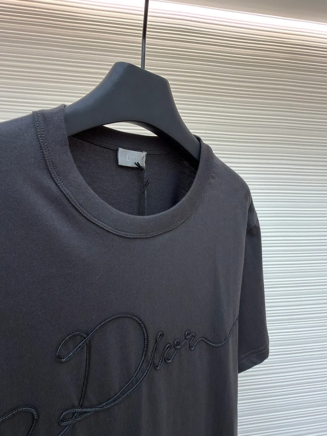 Dior satin emblem round neck short sleeves ●Original version: purchased and developed by 7089 ●Item number: 1681694-A00 ●Fabric: cotton jersey fabric ●Technology: embroidery production ●Color: dark gray ●Version: fitted version ●Weight: about 200 grams ●Size: XS-S-M-L ●Description: The main body is made of 24-count special-spun compact cotton. The weight of 185g/㎡ is light to medium, ensuring the lightness, breathability and good drape of the T-shirt. It is suitable for both spring wear alone and as an inner layer. With 32 pieces of 1×1 rib, 300g/㎡. Its special spinning and compacting process means that compact spinning technology is used in the spinning process, which effectively reduces the hairiness of the yarn, making the yarn smoother and stronger. The woven fabric therefore has the advantages of compact structure, smooth surface, and resistance to pilling. The final dark gray tone is combined with the simple texture of jersey to create a high-end matte texture. Embroidery decoration in the form of satin ribbons, which are fixed on the fabric through special processing. The texture brought by this process is usually different from the woven texture and slight luster of the main knitted fabric. It forms a delicate and accessible visual and tactile focus on the matte dark gray base, enhancing the craftsmanship, design and uniqueness of the single product. The overall wiring is straight and delicate, the fabric is comfortable and soft, and the color is consistent without color difference. It can be matched with the same style to create a fashionable look and control various occasions. Customized accessories, complete with three standards, same style for men and women!