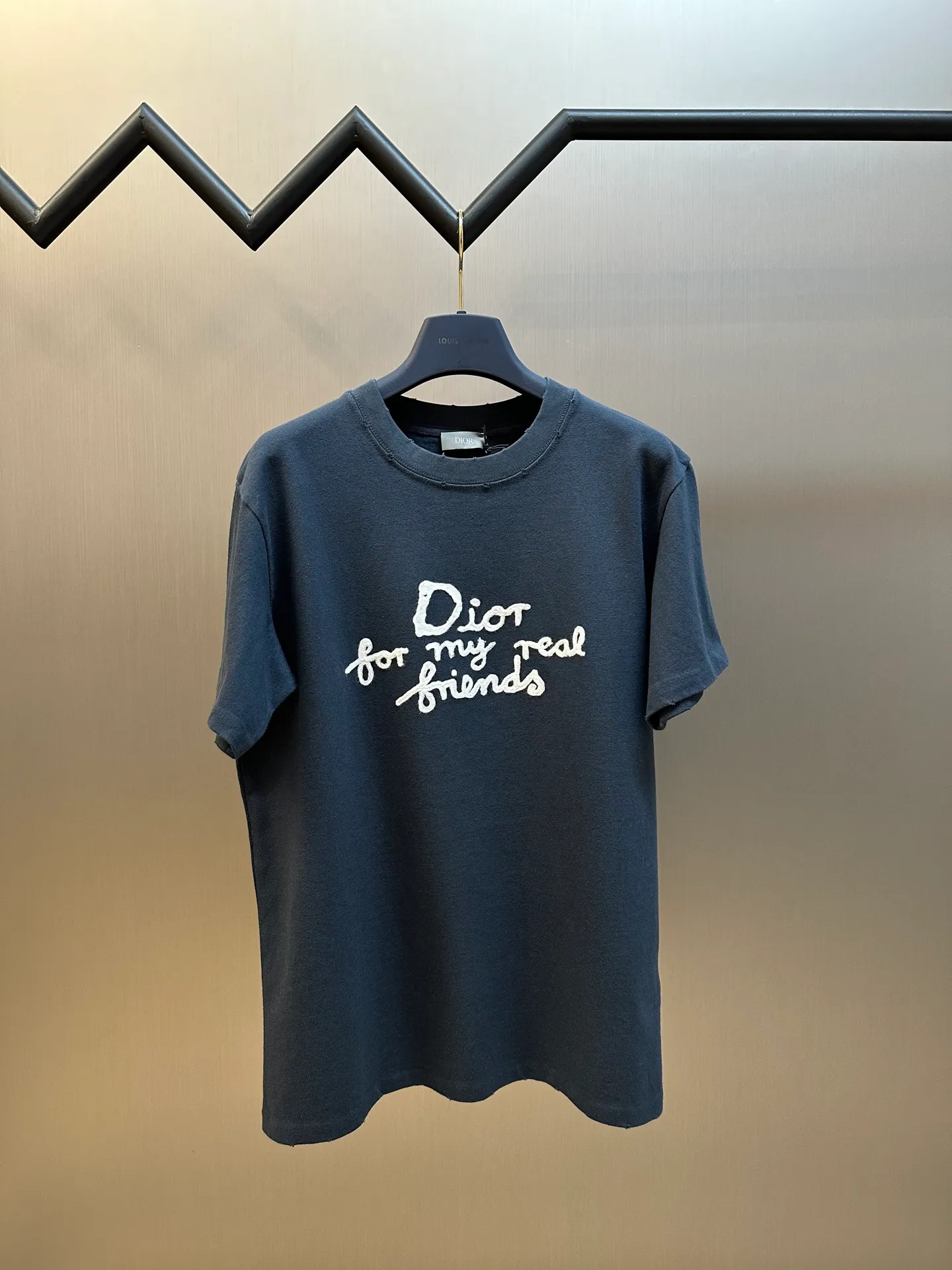 🅿️280 Dior Friends letter embroidered round neck short sleeves are made of pure cotton 12S fine cotton plain weave. The fabric is interwoven with plain weave. The yarns have many buckling points, which makes the fabric have good fastness and wear resistance. The density is moderate, the fabric is thin, flat and stiff. It has good breathability, is softer, more delicate, and has better gloss.  The joint series logo is chain embroidery. Chain embroidery is named because the visual effect of the embroidery is like a chain. The shape is like the links on the chain. It is commonly known as chain embroidery and also called chain eye embroidery. Follow the chain stitch stitch method and embroider from right to left. Maintain the tension of the embroidery thread and the uniformity of the stitches to ensure the three-dimensionality and exquisiteness of the embroidery. It combines the stitching method of chain embroidery with the material of fine wool to create embroidery with chain-like texture and three-dimensional effect.  The whole piece is designed with washed holes and irregular openings all over the body. The simple garments have a rebellious and destructive design. The stone grinding washing process locates the holes, and the ready-to-wear products use the stone grinding machine laser positioning to manually destroy the wear effect. Every wear and tear is made by hand, so that the natural wear and tear of the fabric achieves the most harmonious visual effect. After being washed by stone grinding, it can show a rich retro atmosphere.  The standard round neck and short-sleeved version has a rounded arc neckline, which is suitable for various face shapes and body shapes; the sleeve length is moderate and ends just above the elbow, showing a smart and neat image. The slim fit can show off the wearer's body curves without sacrificing comfort. The collar, cuffs, hem and other parts are all sewn with fine double-needle stitching.  size：xs s m l