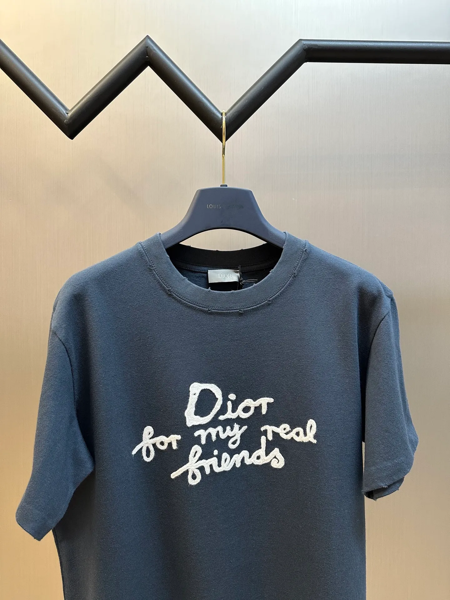 🅿️280 Dior Friends letter embroidered round neck short sleeves are made of pure cotton 12S fine cotton plain weave. The fabric is interwoven with plain weave. The yarns have many buckling points, which makes the fabric have good fastness and wear resistance. The density is moderate, the fabric is thin, flat and stiff. It has good breathability, is softer, more delicate, and has better gloss.  The joint series logo is chain embroidery. Chain embroidery is named because the visual effect of the embroidery is like a chain. The shape is like the links on the chain. It is commonly known as chain embroidery and also called chain eye embroidery. Follow the chain stitch stitch method and embroider from right to left. Maintain the tension of the embroidery thread and the uniformity of the stitches to ensure the three-dimensionality and exquisiteness of the embroidery. It combines the stitching method of chain embroidery with the material of fine wool to create embroidery with chain-like texture and three-dimensional effect.  The whole piece is designed with washed holes and irregular openings all over the body. The simple garments have a rebellious and destructive design. The stone grinding washing process locates the holes, and the ready-to-wear products use the stone grinding machine laser positioning to manually destroy the wear effect. Every wear and tear is made by hand, so that the natural wear and tear of the fabric achieves the most harmonious visual effect. After being washed by stone grinding, it can show a rich retro atmosphere.  The standard round neck and short-sleeved version has a rounded arc neckline, which is suitable for various face shapes and body shapes; the sleeve length is moderate and ends just above the elbow, showing a smart and neat image. The slim fit can show off the wearer's body curves without sacrificing comfort. The collar, cuffs, hem and other parts are all sewn with fine double-needle stitching.  size：xs s m l