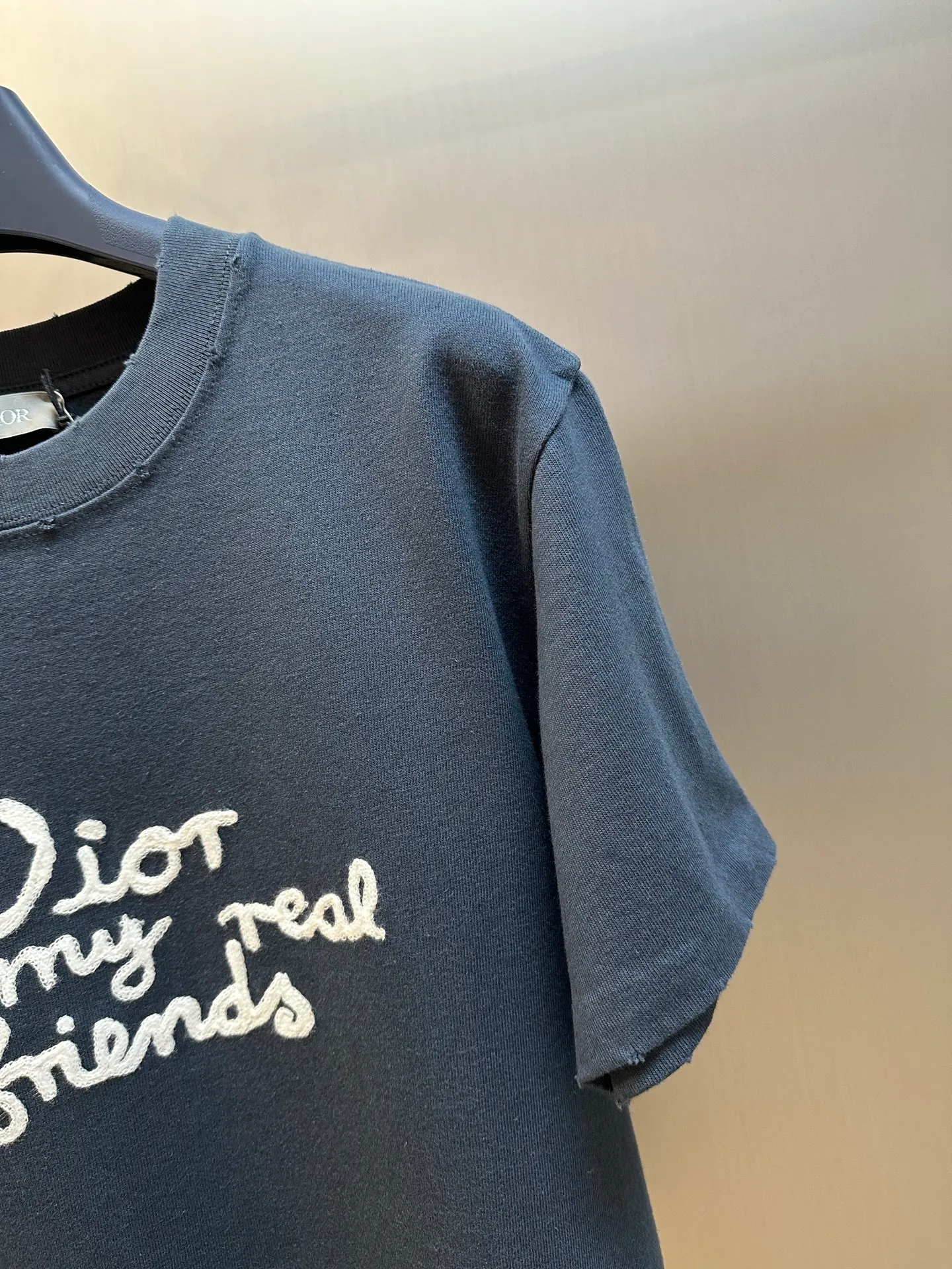 🅿️280 Dior Friends letter embroidered round neck short sleeves are made of pure cotton 12S fine cotton plain weave. The fabric is interwoven with plain weave. The yarns have many buckling points, which makes the fabric have good fastness and wear resistance. The density is moderate, the fabric is thin, flat and stiff. It has good breathability, is softer, more delicate, and has better gloss.  The joint series logo is chain embroidery. Chain embroidery is named because the visual effect of the embroidery is like a chain. The shape is like the links on the chain. It is commonly known as chain embroidery and also called chain eye embroidery. Follow the chain stitch stitch method and embroider from right to left. Maintain the tension of the embroidery thread and the uniformity of the stitches to ensure the three-dimensionality and exquisiteness of the embroidery. It combines the stitching method of chain embroidery with the material of fine wool to create embroidery with chain-like texture and three-dimensional effect.  The whole piece is designed with washed holes and irregular openings all over the body. The simple garments have a rebellious and destructive design. The stone grinding washing process locates the holes, and the ready-to-wear products use the stone grinding machine laser positioning to manually destroy the wear effect. Every wear and tear is made by hand, so that the natural wear and tear of the fabric achieves the most harmonious visual effect. After being washed by stone grinding, it can show a rich retro atmosphere.  The standard round neck and short-sleeved version has a rounded arc neckline, which is suitable for various face shapes and body shapes; the sleeve length is moderate and ends just above the elbow, showing a smart and neat image. The slim fit can show off the wearer's body curves without sacrificing comfort. The collar, cuffs, hem and other parts are all sewn with fine double-needle stitching.  size：xs s m l