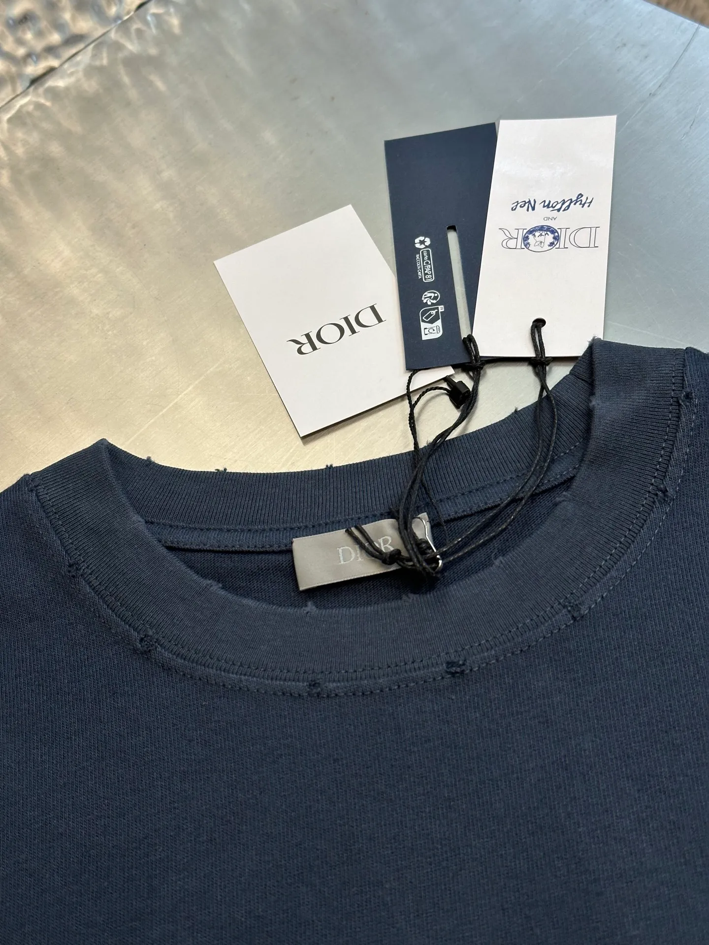 🅿️280 Dior Friends letter embroidered round neck short sleeves are made of pure cotton 12S fine cotton plain weave. The fabric is interwoven with plain weave. The yarns have many buckling points, which makes the fabric have good fastness and wear resistance. The density is moderate, the fabric is thin, flat and stiff. It has good breathability, is softer, more delicate, and has better gloss.  The joint series logo is chain embroidery. Chain embroidery is named because the visual effect of the embroidery is like a chain. The shape is like the links on the chain. It is commonly known as chain embroidery and also called chain eye embroidery. Follow the chain stitch stitch method and embroider from right to left. Maintain the tension of the embroidery thread and the uniformity of the stitches to ensure the three-dimensionality and exquisiteness of the embroidery. It combines the stitching method of chain embroidery with the material of fine wool to create embroidery with chain-like texture and three-dimensional effect.  The whole piece is designed with washed holes and irregular openings all over the body. The simple garments have a rebellious and destructive design. The stone grinding washing process locates the holes, and the ready-to-wear products use the stone grinding machine laser positioning to manually destroy the wear effect. Every wear and tear is made by hand, so that the natural wear and tear of the fabric achieves the most harmonious visual effect. After being washed by stone grinding, it can show a rich retro atmosphere.  The standard round neck and short-sleeved version has a rounded arc neckline, which is suitable for various face shapes and body shapes; the sleeve length is moderate and ends just above the elbow, showing a smart and neat image. The slim fit can show off the wearer's body curves without sacrificing comfort. The collar, cuffs, hem and other parts are all sewn with fine double-needle stitching.  size：xs s m l