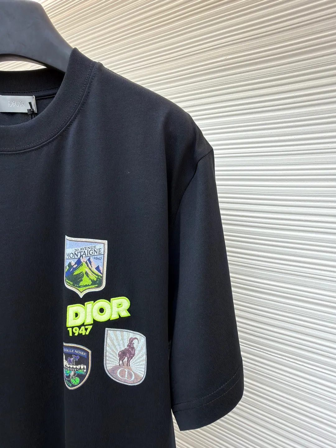 Dior Alpine Embroidery Round Neck Short Sleeve ●Original version: Purchased and developed by 7149 ●Item number: 1681101-X95 ●Fabric: plain knitted fabric ●Technology: white ink direct injection production ●Version: fitted version ●Weight: about 215 grams ●Size: S-M-L-XL ●Description: The main body is made of 24S special woven compact cotton to make plain knitted fabric, weight 180g. High-count combed cotton yarn eliminates most of the short hairiness through compact spinning process, making the yarn smoother and stronger. The woven fabric structure is extremely dense, flat and soft, with excellent anti-pilling ability and durability, while retaining the natural advantages of pure cotton, which is breathable and skin-friendly. The neckline is made of 32S 1x1 rib with a weight of 300g. The finer yarn count creates a more delicate and tight thread, which provides better elasticity and deformation resistance than ordinary ribs, ensuring that the neckline can still remain stiff after being put on and taken off many times. The printed pattern and classic logo inspired by the mountain spirit on the chest become the visual focus through the decoration combined with multiple techniques. The printed pattern elements use digital white ink direct injection technology, which presents bright, opaque white and color patterns on dark fabrics with clear edges and a smooth touch. The classic logo is completed with fluorescent green contrasting letters in the form of patches, which are then precisely sewn onto the fabric using appliqué technology. This process restores the three-dimensionality, color saturation and detail accuracy of the pattern to the original version. With the standard round neck shape and basic color, this product has established a high degree of matching tolerance. It can be mixed and matched with daily jeans or shorts, catering to the pursuit of functionality, comfort and details. The neckline has a rounded arc, suitable for various face shapes and body shapes; the sleeves are moderate and end just above the elbow, showing a smart and neat image. The slim-fitting cut shows off the wearer's body curves without sacrificing comfort. The collar, cuffs, hem and other parts are all sewn with fine double-needle stitching. The overall wiring is straight and delicate, the fabric is comfortable and soft, and the color is consistent without color difference. It can be matched with the same style to create a fashionable look and control various occasions. Customized accessories, complete with three standards, same style for men and women!