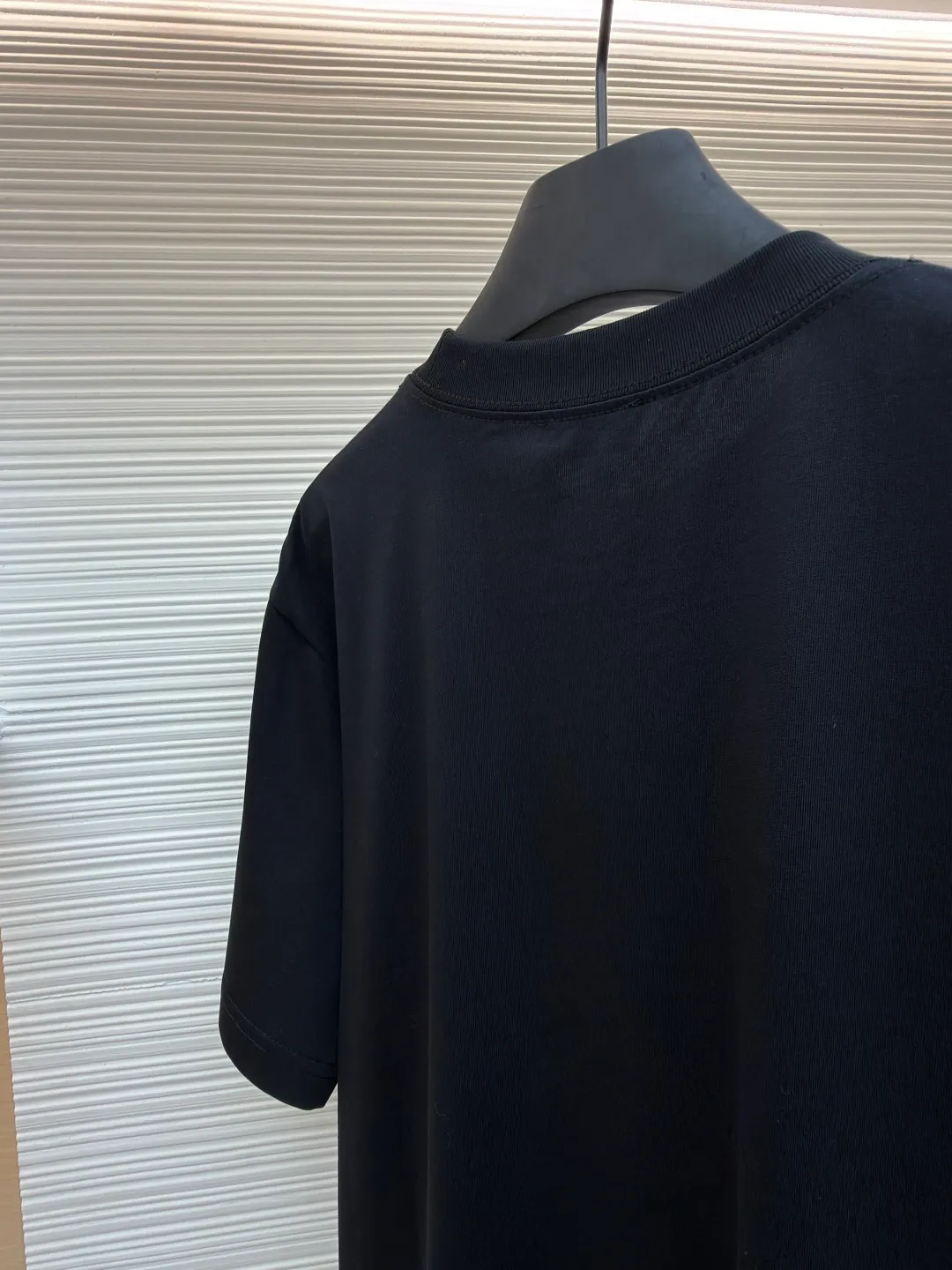 Dior Alpine Embroidery Round Neck Short Sleeve ●Original version: Purchased and developed by 7149 ●Item number: 1681101-X95 ●Fabric: plain knitted fabric ●Technology: white ink direct injection production ●Version: fitted version ●Weight: about 215 grams ●Size: S-M-L-XL ●Description: The main body is made of 24S special woven compact cotton to make plain knitted fabric, weight 180g. High-count combed cotton yarn eliminates most of the short hairiness through compact spinning process, making the yarn smoother and stronger. The woven fabric structure is extremely dense, flat and soft, with excellent anti-pilling ability and durability, while retaining the natural advantages of pure cotton, which is breathable and skin-friendly. The neckline is made of 32S 1x1 rib with a weight of 300g. The finer yarn count creates a more delicate and tight thread, which provides better elasticity and deformation resistance than ordinary ribs, ensuring that the neckline can still remain stiff after being put on and taken off many times. The printed pattern and classic logo inspired by the mountain spirit on the chest become the visual focus through the decoration combined with multiple techniques. The printed pattern elements use digital white ink direct injection technology, which presents bright, opaque white and color patterns on dark fabrics with clear edges and a smooth touch. The classic logo is completed with fluorescent green contrasting letters in the form of patches, which are then precisely sewn onto the fabric using appliqué technology. This process restores the three-dimensionality, color saturation and detail accuracy of the pattern to the original version. With the standard round neck shape and basic color, this product has established a high degree of matching tolerance. It can be mixed and matched with daily jeans or shorts, catering to the pursuit of functionality, comfort and details. The neckline has a rounded arc, suitable for various face shapes and body shapes; the sleeves are moderate and end just above the elbow, showing a smart and neat image. The slim-fitting cut shows off the wearer's body curves without sacrificing comfort. The collar, cuffs, hem and other parts are all sewn with fine double-needle stitching. The overall wiring is straight and delicate, the fabric is comfortable and soft, and the color is consistent without color difference. It can be matched with the same style to create a fashionable look and control various occasions. Customized accessories, complete with three standards, same style for men and women!