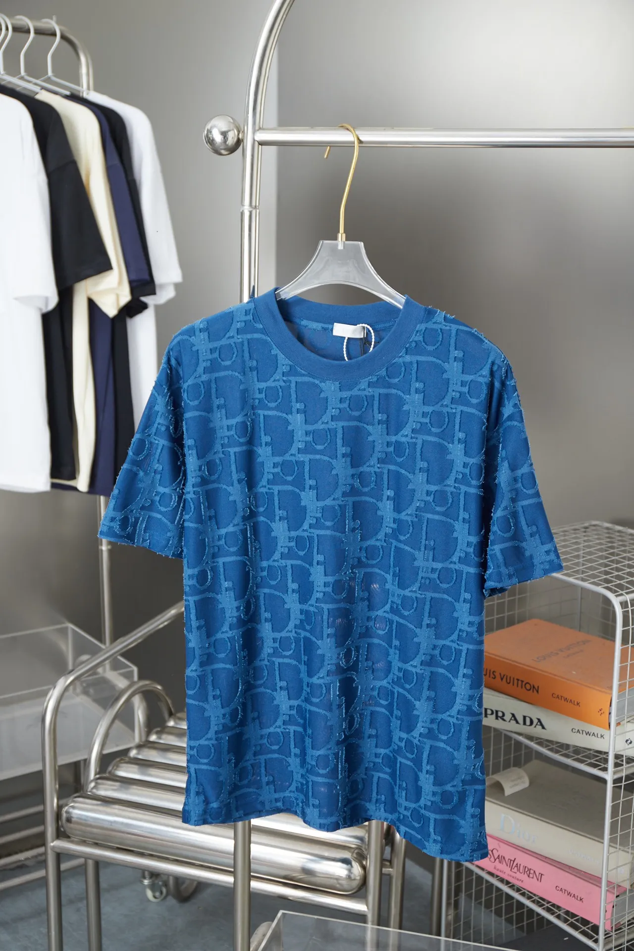 🅿️180 Dior 2025 new style embossed jacquard short-sleeved pure cotton plain fabric, woven with 32S double-strand pure cotton yarn. The 32S double-strand is twisted from two 32-count single yarns. The yarn is thicker and stronger. The fabric has high wear resistance while retaining the moisture absorption and breathability of pure cotton. The plain weave has a tight structure and a smooth surface, but it feels relatively stiff and supports the stiffness of the pattern. The jacquard pattern uses thread-cutting jacquard technology, and the full-width Oblique jacquard pattern forms a relief effect through the deep integration of full-width jacquard and shearing technology. The jacquard structure provides a three-dimensional frame, and the shearing process enhances local texture. The electronic jacquard machine is used to weave complex patterns on the entire fabric to form a three-dimensional concave and convex texture, achieving the integration of texture and pattern. The raised jacquard is cut in a directional manner to create a relief effect, enhancing tactile layering and visual contrast. Straight crew neck fit. Cut and sewn in floral position, standard H hanging fit, with shoulder-length design. The vertical version emphasizes that the width of the shoulders, waist, and hem are basically the same, and it is simple and loose. The short sleeves are tailored to fit the body of the wearer. At the same time, the neckline, cuffs and hem of the short sleeves are all designed with double lines. S M L XL