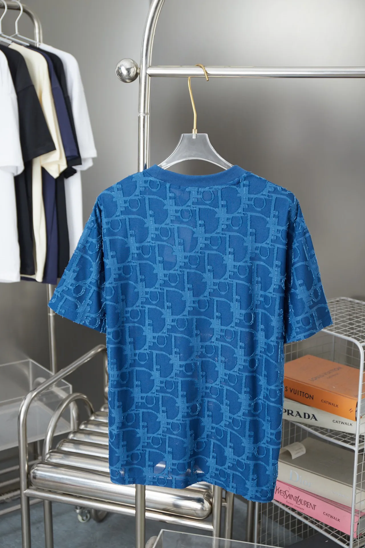 🅿️180 Dior 2025 new style embossed jacquard short-sleeved pure cotton plain fabric, woven with 32S double-strand pure cotton yarn. The 32S double-strand is twisted from two 32-count single yarns. The yarn is thicker and stronger. The fabric has high wear resistance while retaining the moisture absorption and breathability of pure cotton. The plain weave has a tight structure and a smooth surface, but it feels relatively stiff and supports the stiffness of the pattern. The jacquard pattern uses thread-cutting jacquard technology, and the full-width Oblique jacquard pattern forms a relief effect through the deep integration of full-width jacquard and shearing technology. The jacquard structure provides a three-dimensional frame, and the shearing process enhances local texture. The electronic jacquard machine is used to weave complex patterns on the entire fabric to form a three-dimensional concave and convex texture, achieving the integration of texture and pattern. The raised jacquard is cut in a directional manner to create a relief effect, enhancing tactile layering and visual contrast. Straight crew neck fit. Cut and sewn in floral position, standard H hanging fit, with shoulder-length design. The vertical version emphasizes that the width of the shoulders, waist, and hem are basically the same, and it is simple and loose. The short sleeves are tailored to fit the body of the wearer. At the same time, the neckline, cuffs and hem of the short sleeves are all designed with double lines. S M L XL