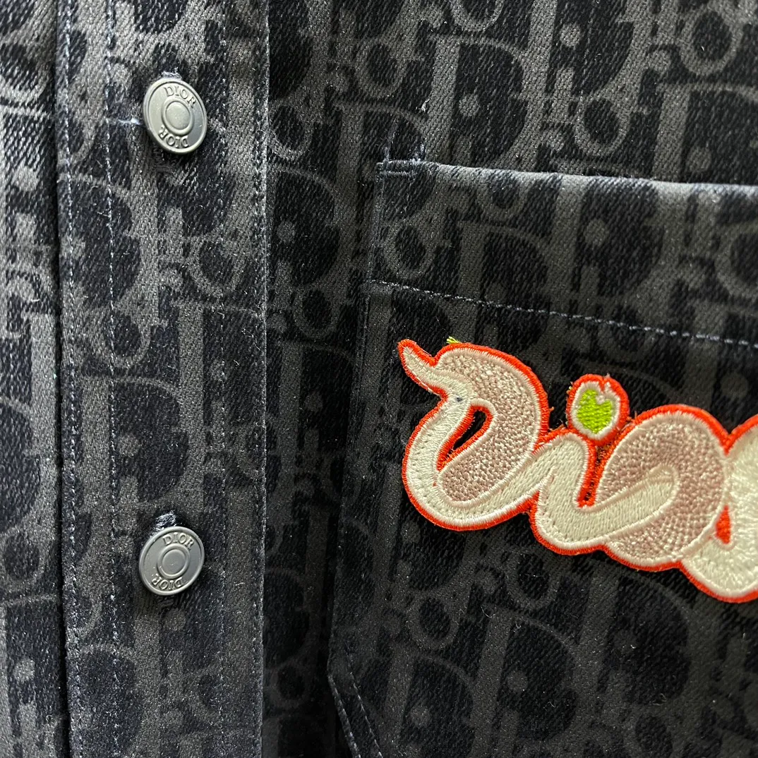 🅿️630 🧧CD blue cotton blended denim fabric jacket shirt SIZE: S-XL This jacket shirt is from the DIOR AND KAWS limited series. Crafted from blue cotton-blend denim, it features the classic Oblique print throughout, complemented by green DIOR AND KAWS embroidery, which reinterprets the Dior logo in a colorful snake shape. Featuring two chest patch pockets, it can be paired with jeans or shorts for a casual yet stylish look.