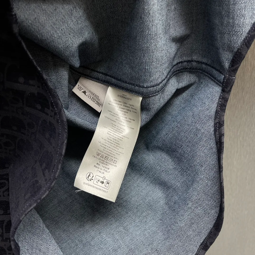 🅿️630 🧧CD blue cotton blended denim fabric jacket shirt SIZE: S-XL This jacket shirt is from the DIOR AND KAWS limited series. Crafted from blue cotton-blend denim, it features the classic Oblique print throughout, complemented by green DIOR AND KAWS embroidery, which reinterprets the Dior logo in a colorful snake shape. Featuring two chest patch pockets, it can be paired with jeans or shorts for a casual yet stylish look.