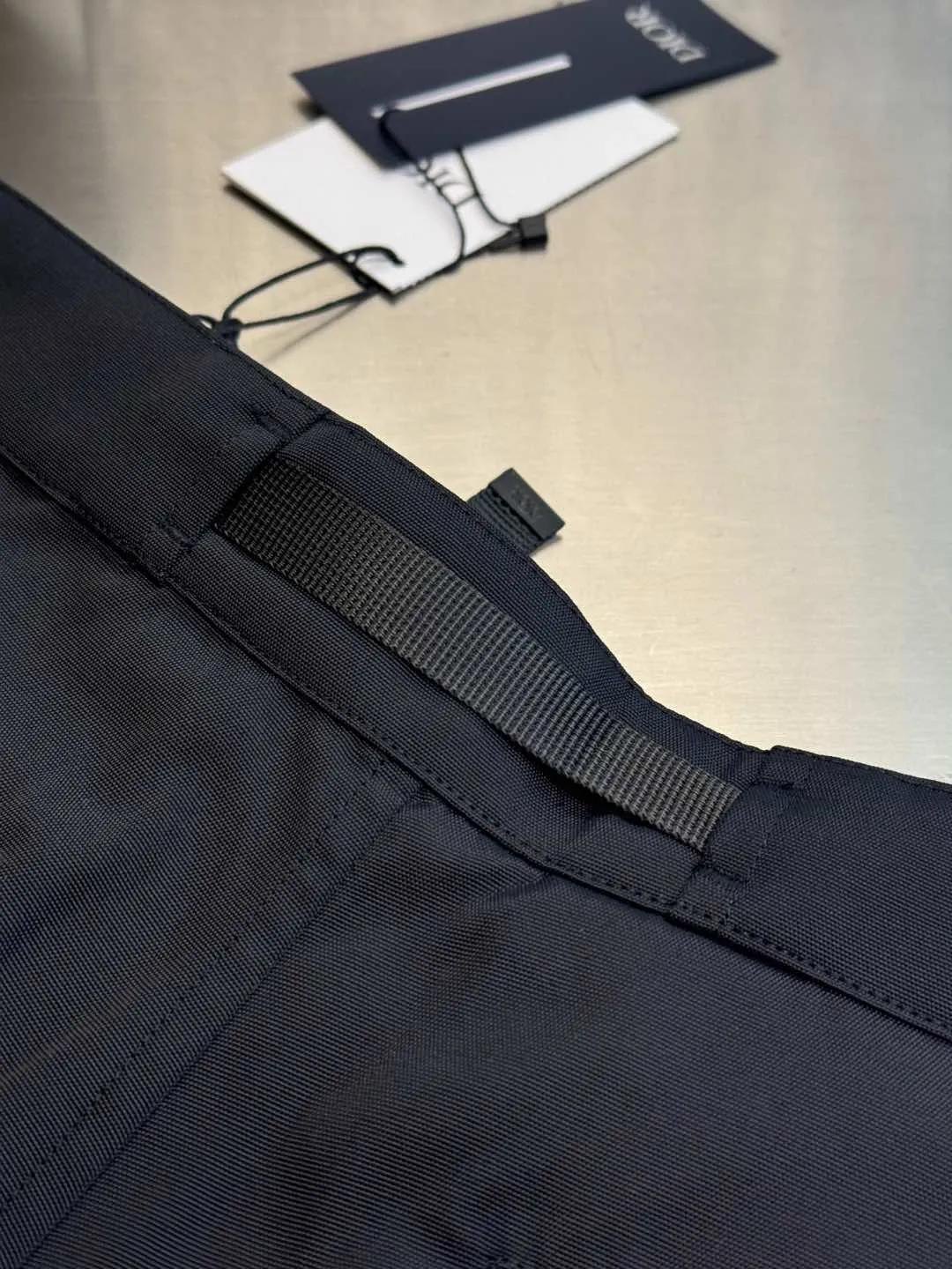 🅿️560 Dior metal buckle web trousers are made of small pique nylon fabric, customized with exclusive warp pulling on the beam to make a jacquard pan head, high-speed rapier weaving, matching 60s twill imitation Tencel cotton lining, and custom-made waistband hardware locks. The parts are hand-sprayed with glossy black paint, laser engraved with letters, side pockets with CD lettering and lacquered snap buttons, silicone stamp on the rear panel, scanned the original version and made three template corrections, 3D printed and molded in one step size: 44.46.48.50