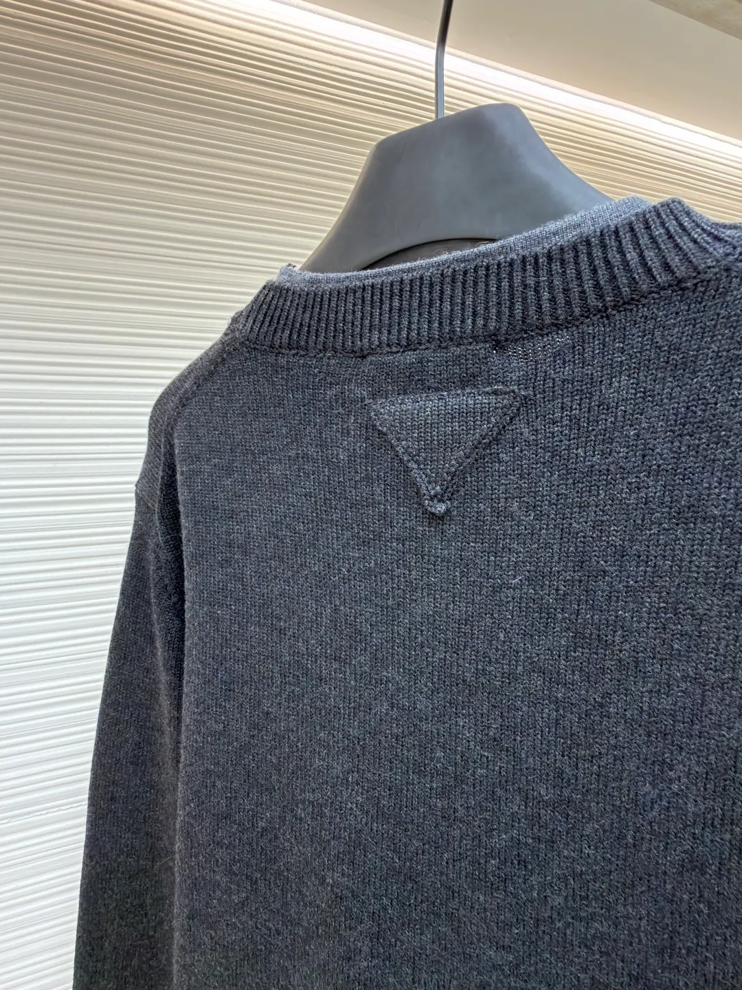 Prada round neck rib knitted cuffs and hem logo sweater ●Original version: Purchased and developed by 13114 ●Item number: 1682312-A90 ●Fabric: wool fabric ●Technology: knitted ●Color: gray ●Version: fitted version ●Weight: about 765 grams ●Size: S-M-L-XL ●Description: This Prada knitted round-neck top is woven with high-count blended wool yarn imported from Italy. It is treated with a double-ply yarn process to increase the yarn's toughness by 30%, while giving the fabric a delicate matte texture and a soft and skin-friendly touch. The main body of the garment uses a 12-needle four-flat knitting method and is designed with vertical rib texture, which not only ensures a stiff silhouette and is not easily deformed, but also allows for freedom of stretching while wearing. The neckline, cuffs and hem adopt reinforced ribbing technology, and the elastic closing is formed by precise jacquard using a computerized flat knitting machine, effectively preventing loose and curling edges. The brand metal nameplate is embedded in the side seam, which is hand-polished and then seamlessly sewn together. The splicing parts of the body are all made of concealed seam technology, making the overall lines simple and smooth. Every detail demonstrates the brand's exquisite clothing craftsmanship and strict quality control. The overall wiring is straight and delicate, the fabric is comfortable and soft, and the color is consistent without color difference. It can be matched with the same style to create a fashionable look and control various occasions. Customized accessories, complete with three standards, same style for men and women!