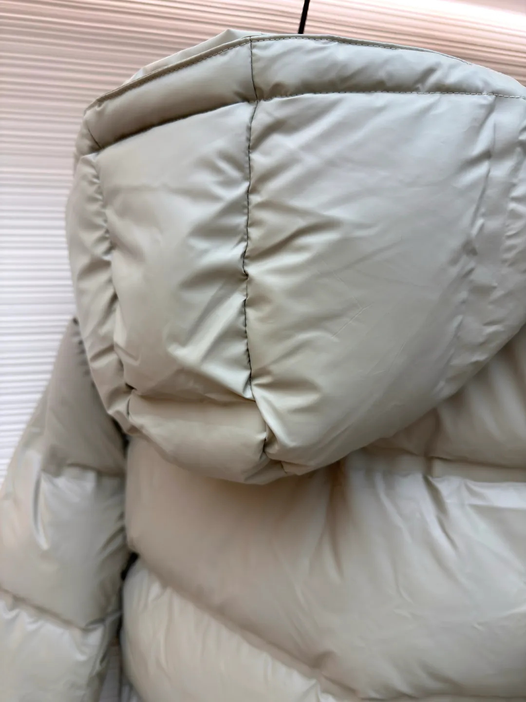 Prada solid color down jacket with removable hood ●Item number: 1682018-D15 ●Fabric: white duck down fabric ●Technology: mechanical down filling ●Color: light khaki gray ●Version: fitted version ●Weight: about 1070 grams ●Size: 48-50-52-54-56 ●Description: This Prada down jacket is made of regenerated nylon fabric, which is treated with high-density weaving and Teflon coating. It is waterproof and wrinkle-resistant and has a matte soft texture. The filling is made of 90% white duck down, and the down is locked in zones through 65-degree diagonal quilting technology. The stitch length is precisely controlled at 3 stitches/cm to avoid down fleece and give the body three-dimensional bulk. The detachable hood is fixed with metal snaps, and the bevel stitching on the neckline improves the fit; the triangle logo on the chest is presented in metal relief, seamlessly connecting with the same-color stitching on the body. The cuffs and hem are equipped with elastic ribs, the side invisible zipper pockets are hot-melt bonded, and the brand's customized hardware accessories are used in every detail, taking into account functionality and luxury texture. The overall wiring is straight and delicate, the fabric is comfortable and soft, and the color is consistent without color difference. It can be matched with the same style to create a fashionable look and control various occasions. Customized accessories, complete with three standards, same style for men and women!