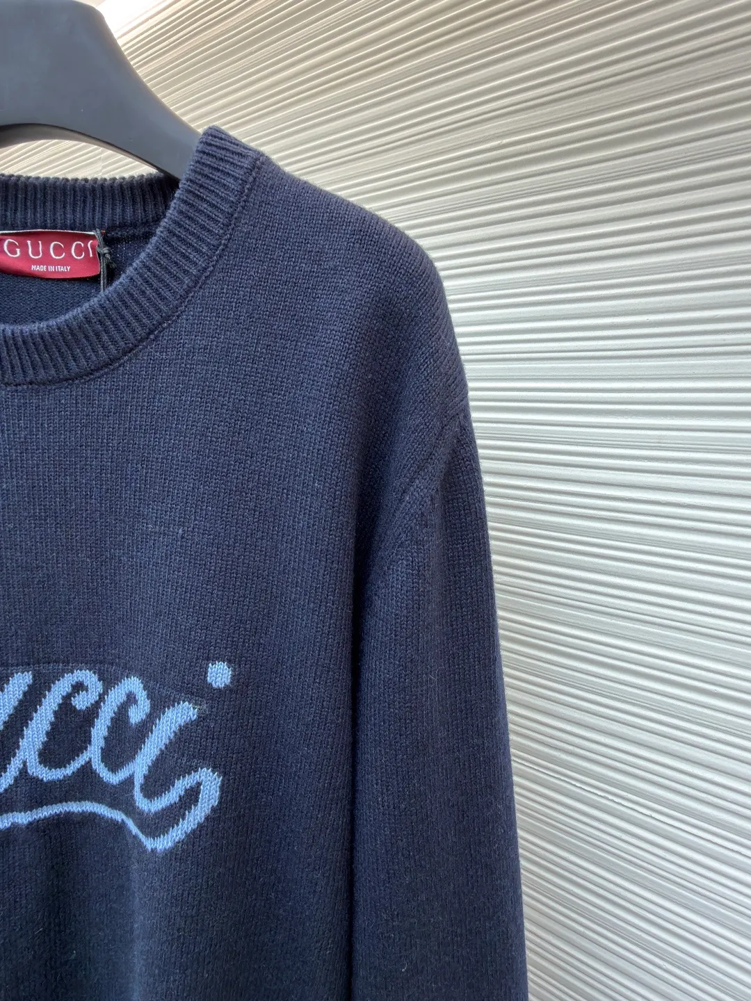 Gucci intarsia knitted wool crew neck sweater ●Original version: purchased and developed by 10024 ●Item number: 1681824-A85 ●Fabric: wool blended fabric ●Technology: knitted intarsia production ●Color: navy blue ●Version: fitted version ●Weight: about 540 grams ●Size: XS-S-M-L ●Description: This Gucci navy blue sweater is made of worsted wool blended fabric with fine flat stitch as the base, which is soft to the touch and has good warmth retention. The core logo of the garment uses contrasting jacquard technology: the light blue font is presented in a three-dimensional texture, and the strokes are smooth and delicate, forming a soft layer with the navy blue background, while retaining the recognition of the brand logo; the collar, cuffs and hem are all ribbed knitted structures, with elastic edges to ensure fit and durability. The body shape is cut with loose shoulders, and the stitching is neat without unnecessary threads. The jacquard texture and the base knitting are naturally connected, which not only reflects the fine workmanship of luxury items, but also makes it comfortable and casual for daily wear. The overall wiring is straight and delicate, the fabric is comfortable and soft, and the color is consistent without color difference. It can be matched with the same style to create a fashionable look and control various occasions. Customized accessories, complete with three standards, same style for men and women!