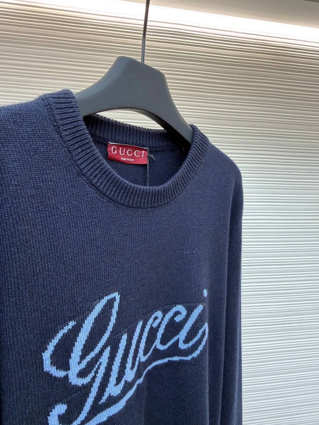 Gucci intarsia knitted wool crew neck sweater ●Original version: purchased and developed by 10024 ●Item number: 1681824-A85 ●Fabric: wool blended fabric ●Technology: knitted intarsia production ●Color: navy blue ●Version: fitted version ●Weight: about 540 grams ●Size: XS-S-M-L ●Description: This Gucci navy blue sweater is made of worsted wool blended fabric with fine flat stitch as the base, which is soft to the touch and has good warmth retention. The core logo of the garment uses contrasting jacquard technology: the light blue font is presented in a three-dimensional texture, and the strokes are smooth and delicate, forming a soft layer with the navy blue background, while retaining the recognition of the brand logo; the collar, cuffs and hem are all ribbed knitted structures, with elastic edges to ensure fit and durability. The body shape is cut with loose shoulders, and the stitching is neat without unnecessary threads. The jacquard texture and the base knitting are naturally connected, which not only reflects the fine workmanship of luxury items, but also makes it comfortable and casual for daily wear. The overall wiring is straight and delicate, the fabric is comfortable and soft, and the color is consistent without color difference. It can be matched with the same style to create a fashionable look and control various occasions. Customized accessories, complete with three standards, same style for men and women!
