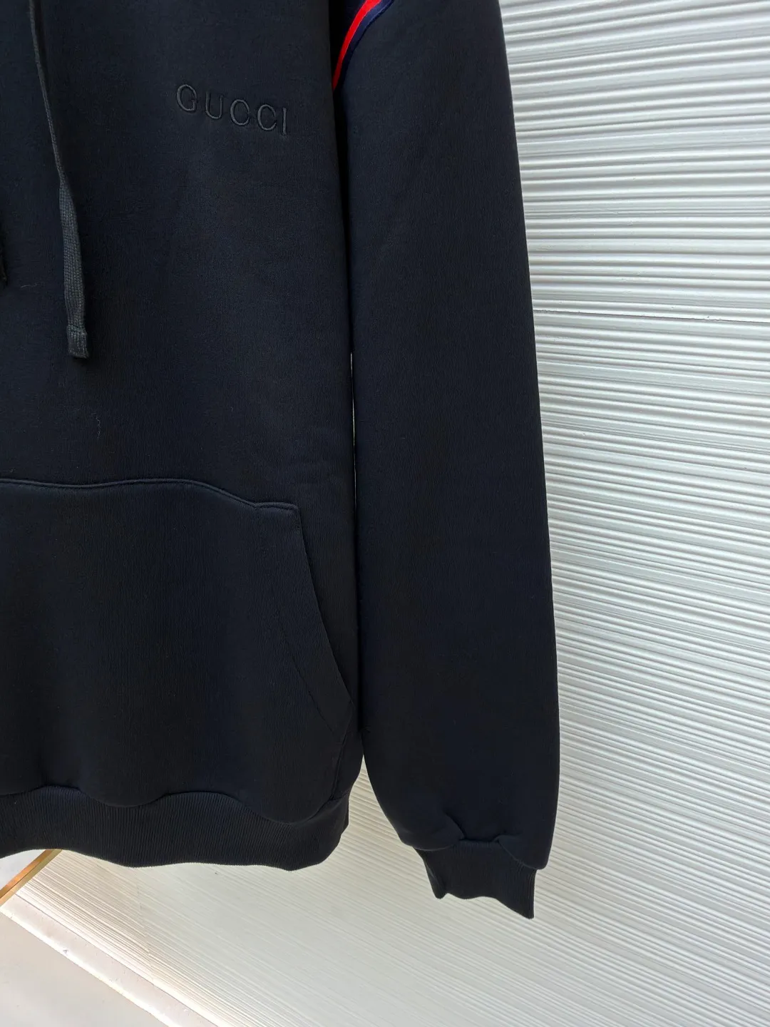 Gucci black webbing hooded sweatshirt ●Item number: 1681424-B10 ●Material: cotton terry fabric ●Technology: embroidery production ●Color: black ●Version: fitted version ●Weight: about 695 grams ●Size: S-M-L ●Description: This sweatshirt is made of high-density waffle velvet fabric, which feels thick and has good warmth retention. The hooded design adopts three-dimensional tailoring and drawstring technology. The hood is stiff and can be freely adjusted for tightness. The red and blue webbing on the shoulders uses inlay sewing technology to form a sharp visual contrast with the black fabric, and the lines are smooth and firm. The brand logo on the chest uses high-density embroidery technology, and the letter texture is delicate and closely adheres to the fabric. The kangaroo pocket is made of one-piece molding technology, with flat edges and convenient storage. The cuffs and hem ribs are made of high-elastic knitting technology, which closely fits the body and has excellent elasticity. The overall cut is a loose, dropped-shoulder version, and the multi-piece structure is spliced ​​to create a casual and trendy wearing effect, while ensuring comfort and freedom during movement. It is a fashionable item that combines the brand's classic elements with casual sweatshirt technology, and has both texture and practicality. The overall wiring is straight and delicate, the fabric is comfortable and soft, and the color is consistent without color difference. It can be matched with the same style to create a fashionable look and control various occasions. Customized accessories, complete with three standards, same style for men and women!
