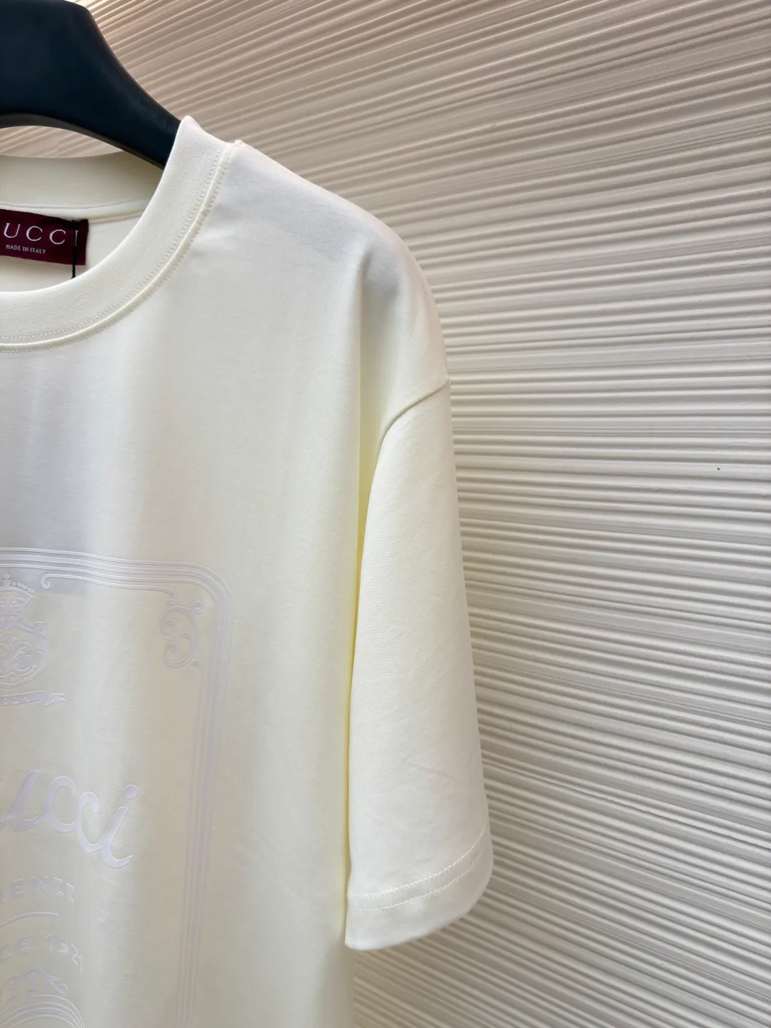 Gucci Buddha City printed round neck short sleeves ●Original version: purchased and developed by 5039 ●Item number: 1682280-A00 ●Fabric: soft knitted cotton fabric ●Technology: glue printing ●Color: apricot ●Version: fitted version ●Weight: about 245 grams ●Size: XS-S-M-L ●Description: This product is made of 60-count single-yarn double-sided knitted cotton with a weight of 170g/㎡; the neckline and other parts are matched with 32-count double-yarn ribbing. The high weight ensures a stable collar shape. 60 counts is an extremely high count, which means the yarn is extremely fine, which directly gives the fabric an extraordinary delicate, silky and soft touch. The front and back sides of the double-sided fabric have the same texture, which is uniform, thin and elastic. The weight of 170g is lightweight, ensuring the T-shirt is extremely light, breathable and drapey. It is almost invisible when worn and is very suitable for early spring. The color of the fabric is soft and high-end, which further enhances the exquisite texture of the fabric. The direct expression of the printing collection elements uses the environmentally friendly elastic thick plate bright glue printing process to place such a three-dimensional, bright, and highly present slogan printing on the simple sweater. This is a high-end special printing technology. Thick plate means that the slurry is accumulated thickly, which can form an obvious three-dimensional effect; after the bright slurry is cured, the surface will show a high-gloss glossy effect; the slurry itself is elastic and can stretch with the fabric. The special environmentally friendly elastic bright slurry is transferred through thick coating on the screen and then solidified at high temperature. Create a brand slogan pattern with significant 3D raised texture, mirror-like luster, and strong stretch resistance. To the touch, the pattern area has obvious stiff bulges and a smooth lacquered surface, which forms a strong contrast with the extremely soft fabric base and has a strong visual impact. The overall wiring is straight and delicate, the fabric is comfortable and soft, and the color is consistent without color difference. It can be matched with the same style to create a fashionable look and control various occasions. Customized accessories, complete with three standards, same style for men and women!