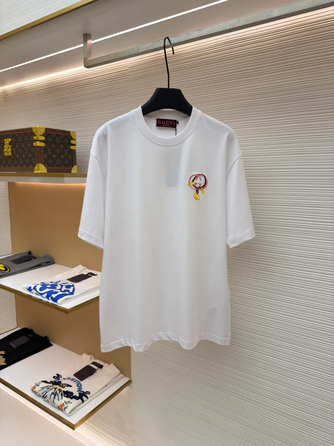 Gucci horseshoe buckle embroidered round neck short sleeves ●Item number: 1682116-A00 ●Material: fine velvet knitted cotton fabric ●Technology: embroidery production ●Color: white ●Version: fitted version ●Weight: about 270 grams ●Size: XS-S-M-L ●Description: Made of 15S special woven compact cotton fine velvet knitted fabric with a weight of 230g/㎡; paired with 32S high count and high weight 1x1 rib, with a weight of 340g/㎡. Ribbing is used on the collar to ensure excellent elastic recovery and deformation resistance of the collar. The fabric uses compact spinning technology to effectively reduce yarn hairiness, making the fabric structure tighter, the surface smoother, and the pilling resistance better. The weight of 230g is medium to heavy, which gives the T-shirt good stiffness and drape, and is not easy to collapse, ensuring the texture of high-end ready-to-wear. The fine velvet knitted fabric has been lightly brushed or raised, giving it a softer, waxier skin-friendly feel than ordinary plain cotton. Using multi-color fine flat embroidery technology, the pattern is completely covered and filled with extremely high-density stitches using embroidery threads of multiple colors according to the design artwork. Every detail and color transition of the complex pattern is accurately restored, so that the shape, light, shadow, and texture of the double-G interlocking webbing and stirrups are clearly presented. The final embroidery surface is flat, smooth, and full, with clear edges, and has a delicate effect and micro-three-dimensional effect similar to gongbi painting. The overall wiring is straight and delicate, the fabric is comfortable and soft, and the color is consistent without color difference. It can be matched with the same style to create a fashionable look and control various occasions. Customized accessories, complete with three standards, same style for men and women!