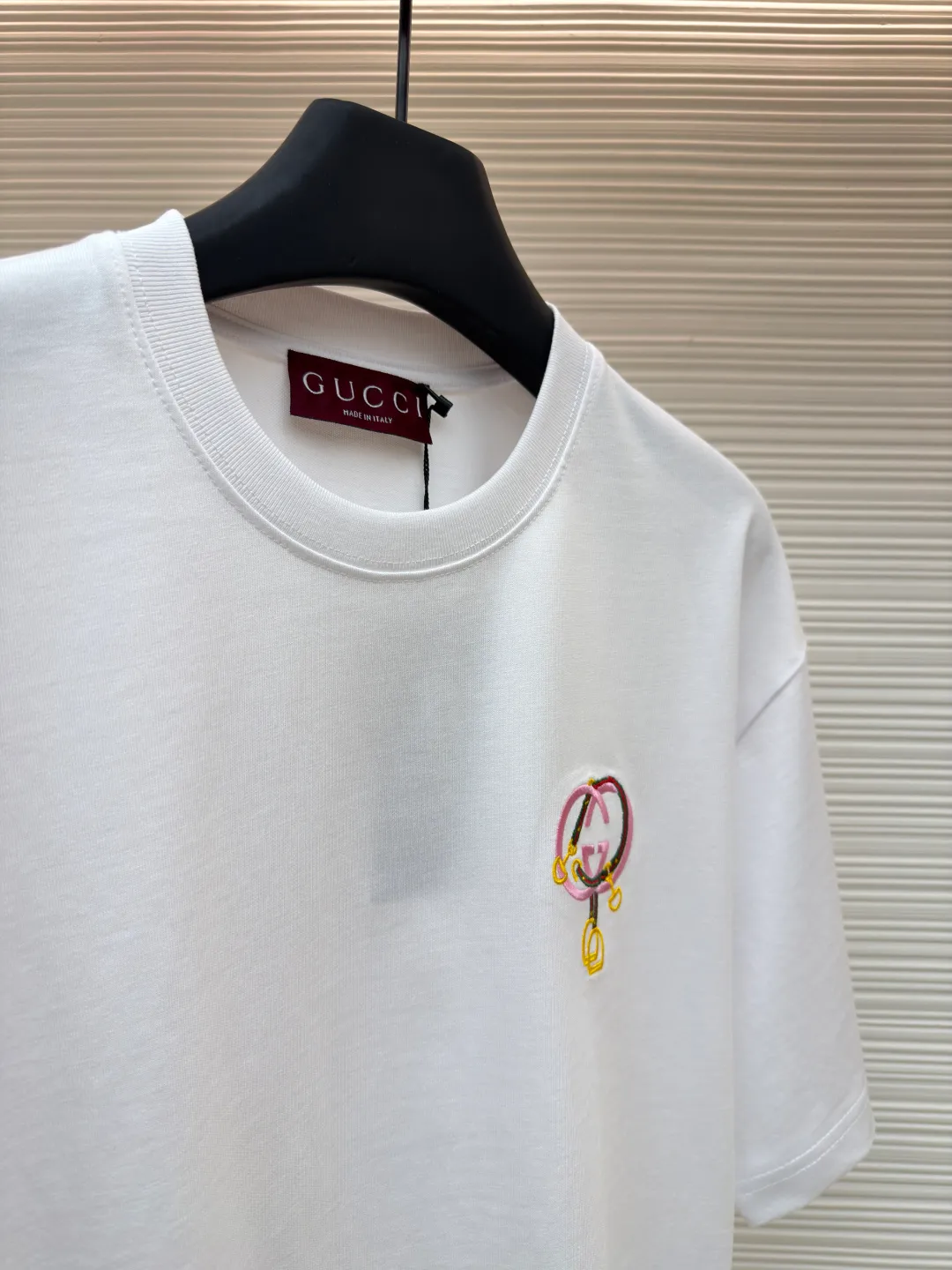 Gucci horseshoe buckle embroidered round neck short sleeves ●Item number: 1682116-A00 ●Material: fine velvet knitted cotton fabric ●Technology: embroidery production ●Color: white ●Version: fitted version ●Weight: about 270 grams ●Size: XS-S-M-L ●Description: Made of 15S special woven compact cotton fine velvet knitted fabric with a weight of 230g/㎡; paired with 32S high count and high weight 1x1 rib, with a weight of 340g/㎡. Ribbing is used on the collar to ensure excellent elastic recovery and deformation resistance of the collar. The fabric uses compact spinning technology to effectively reduce yarn hairiness, making the fabric structure tighter, the surface smoother, and the pilling resistance better. The weight of 230g is medium to heavy, which gives the T-shirt good stiffness and drape, and is not easy to collapse, ensuring the texture of high-end ready-to-wear. The fine velvet knitted fabric has been lightly brushed or raised, giving it a softer, waxier skin-friendly feel than ordinary plain cotton. Using multi-color fine flat embroidery technology, the pattern is completely covered and filled with extremely high-density stitches using embroidery threads of multiple colors according to the design artwork. Every detail and color transition of the complex pattern is accurately restored, so that the shape, light, shadow, and texture of the double-G interlocking webbing and stirrups are clearly presented. The final embroidery surface is flat, smooth, and full, with clear edges, and has a delicate effect and micro-three-dimensional effect similar to gongbi painting. The overall wiring is straight and delicate, the fabric is comfortable and soft, and the color is consistent without color difference. It can be matched with the same style to create a fashionable look and control various occasions. Customized accessories, complete with three standards, same style for men and women!
