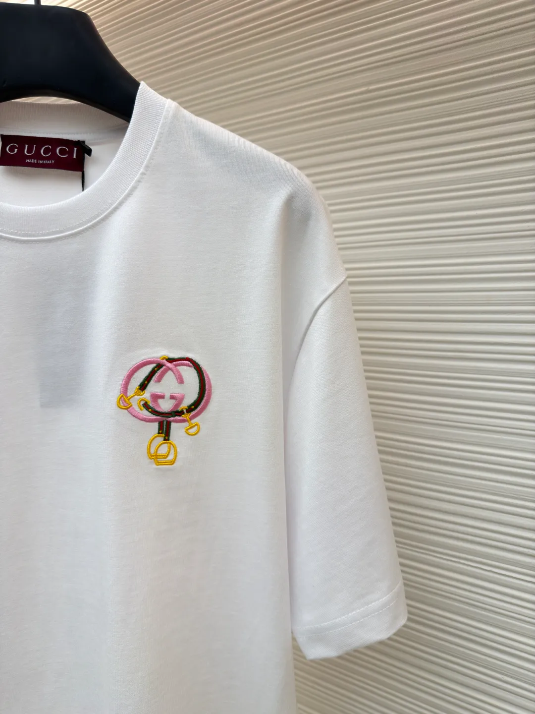 Gucci horseshoe buckle embroidered round neck short sleeves ●Item number: 1682116-A00 ●Material: fine velvet knitted cotton fabric ●Technology: embroidery production ●Color: white ●Version: fitted version ●Weight: about 270 grams ●Size: XS-S-M-L ●Description: Made of 15S special woven compact cotton fine velvet knitted fabric with a weight of 230g/㎡; paired with 32S high count and high weight 1x1 rib, with a weight of 340g/㎡. Ribbing is used on the collar to ensure excellent elastic recovery and deformation resistance of the collar. The fabric uses compact spinning technology to effectively reduce yarn hairiness, making the fabric structure tighter, the surface smoother, and the pilling resistance better. The weight of 230g is medium to heavy, which gives the T-shirt good stiffness and drape, and is not easy to collapse, ensuring the texture of high-end ready-to-wear. The fine velvet knitted fabric has been lightly brushed or raised, giving it a softer, waxier skin-friendly feel than ordinary plain cotton. Using multi-color fine flat embroidery technology, the pattern is completely covered and filled with extremely high-density stitches using embroidery threads of multiple colors according to the design artwork. Every detail and color transition of the complex pattern is accurately restored, so that the shape, light, shadow, and texture of the double-G interlocking webbing and stirrups are clearly presented. The final embroidery surface is flat, smooth, and full, with clear edges, and has a delicate effect and micro-three-dimensional effect similar to gongbi painting. The overall wiring is straight and delicate, the fabric is comfortable and soft, and the color is consistent without color difference. It can be matched with the same style to create a fashionable look and control various occasions. Customized accessories, complete with three standards, same style for men and women!