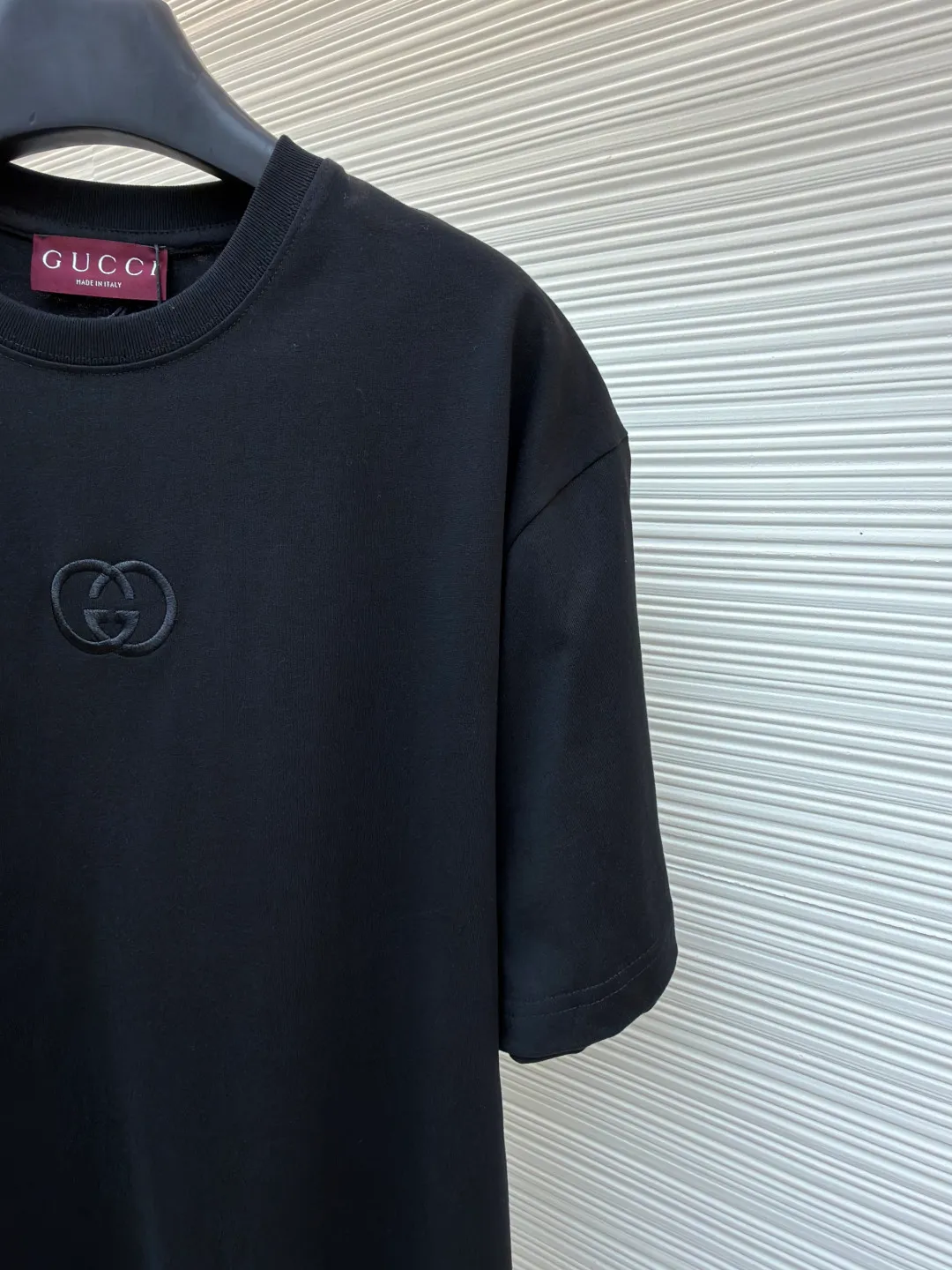 Gucci Double G embroidered round neck short sleeves ●Original version: Purchased and developed for 5300 ●Item number: 1682500-X90 ●Fabric: fine velvet knitted cotton fabric ●Technology: embroidery production ●Color: black ●Version: fitted version ●Weight: about 295 grams ●Size: S-M-L-XL ●Description: Made of 15S special woven compact cotton fine velvet knitted fabric with a weight of 230g/㎡; paired with 32S high count and high weight 1x1 rib, with a weight of 340g/㎡. Ribbing is used on the collar to ensure excellent elastic recovery and deformation resistance of the collar. The fabric uses compact spinning technology to effectively reduce yarn hairiness, making the fabric structure tighter, the surface smoother, and the pilling resistance better. The weight of 230g is medium to heavy, which gives the T-shirt good stiffness and drape, and is not easy to collapse, ensuring the texture of high-end ready-to-wear. The fine velvet knitted fabric has been lightly brushed or raised, giving it a softer, waxier skin-friendly feel than ordinary plain cotton. Three-dimensional stitch embroidery is an embroidery process that uses high-density linear stitches to be closely arranged to form raised lines. The core is to use thicker embroidery thread, and the stitches are continuous and even without gaps. It naturally produces a raised height of 1-2 mm, making the edges of the pattern clear and sharp, and the touch feeling full and solid. The overall wiring is straight and delicate, the fabric is comfortable and soft, and the color is consistent without color difference. It can be matched with the same style to create a fashionable look and control various occasions. Customized accessories, complete with three standards, same style for men and women!
