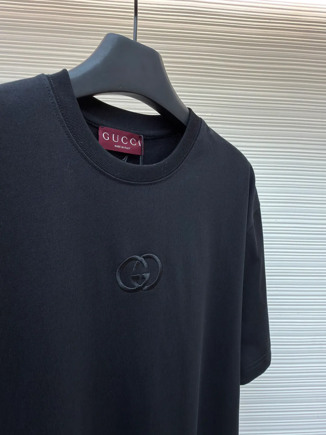 Gucci Double G embroidered round neck short sleeves ●Original version: Purchased and developed for 5300 ●Item number: 1682500-X90 ●Fabric: fine velvet knitted cotton fabric ●Technology: embroidery production ●Color: black ●Version: fitted version ●Weight: about 295 grams ●Size: S-M-L-XL ●Description: Made of 15S special woven compact cotton fine velvet knitted fabric with a weight of 230g/㎡; paired with 32S high count and high weight 1x1 rib, with a weight of 340g/㎡. Ribbing is used on the collar to ensure excellent elastic recovery and deformation resistance of the collar. The fabric uses compact spinning technology to effectively reduce yarn hairiness, making the fabric structure tighter, the surface smoother, and the pilling resistance better. The weight of 230g is medium to heavy, which gives the T-shirt good stiffness and drape, and is not easy to collapse, ensuring the texture of high-end ready-to-wear. The fine velvet knitted fabric has been lightly brushed or raised, giving it a softer, waxier skin-friendly feel than ordinary plain cotton. Three-dimensional stitch embroidery is an embroidery process that uses high-density linear stitches to be closely arranged to form raised lines. The core is to use thicker embroidery thread, and the stitches are continuous and even without gaps. It naturally produces a raised height of 1-2 mm, making the edges of the pattern clear and sharp, and the touch feeling full and solid. The overall wiring is straight and delicate, the fabric is comfortable and soft, and the color is consistent without color difference. It can be matched with the same style to create a fashionable look and control various occasions. Customized accessories, complete with three standards, same style for men and women!