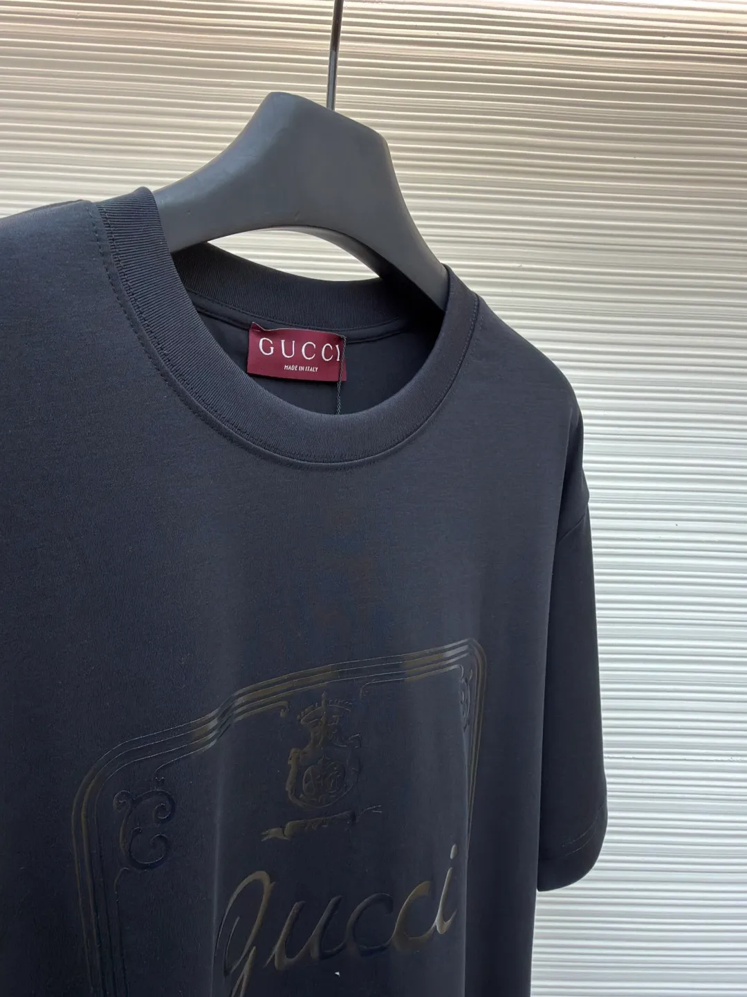 Gucci Buddha City printed round neck short sleeves ●Original version: purchased and developed by 5039 ●Item number: 1682281-A00 ●Fabric: soft knitted cotton fabric ●Technology: Glue printing production ●Color: black ●Version: fitted version ●Weight: about 235 grams ●Size: XS-S-M-L ●Description: This product is made of 60-count single-yarn double-sided knitted cotton with a weight of 170g/㎡; the neckline and other parts are matched with 32-count double-yarn ribbing. The high weight ensures a stable collar shape. 60 counts is an extremely high count, which means the yarn is extremely fine, which directly gives the fabric an extraordinary delicate, silky and soft touch. The front and back sides of the double-sided fabric have the same texture, which is uniform, thin and elastic. The weight of 170g is lightweight, ensuring the T-shirt is extremely light, breathable and drapey. It is almost invisible when worn and is very suitable for early spring. The color of the fabric is soft and high-end, which further enhances the exquisite texture of the fabric. The direct expression of the printing collection elements uses the environmentally friendly elastic thick plate bright glue printing process to place such a three-dimensional, bright, and highly present slogan printing on the simple sweater. This is a high-end special printing technology. Thick plate means that the slurry is accumulated thickly, which can form an obvious three-dimensional effect; after the bright slurry is cured, the surface will show a high-gloss glossy effect; the slurry itself is elastic and can stretch with the fabric. The special environmentally friendly elastic bright slurry is transferred through thick coating on the screen and then solidified at high temperature. Create a brand slogan pattern with significant 3D raised texture, mirror-like luster, and strong stretch resistance. To the touch, the pattern area has obvious stiff bulges and a smooth lacquered surface, which forms a strong contrast with the extremely soft fabric base and has a strong visual impact. The overall wiring is straight and delicate, the fabric is comfortable and soft, and the color is consistent without color difference. It can be matched with the same style to create a fashionable look and control various occasions. Customized accessories, complete with three standards, same style for men and women!