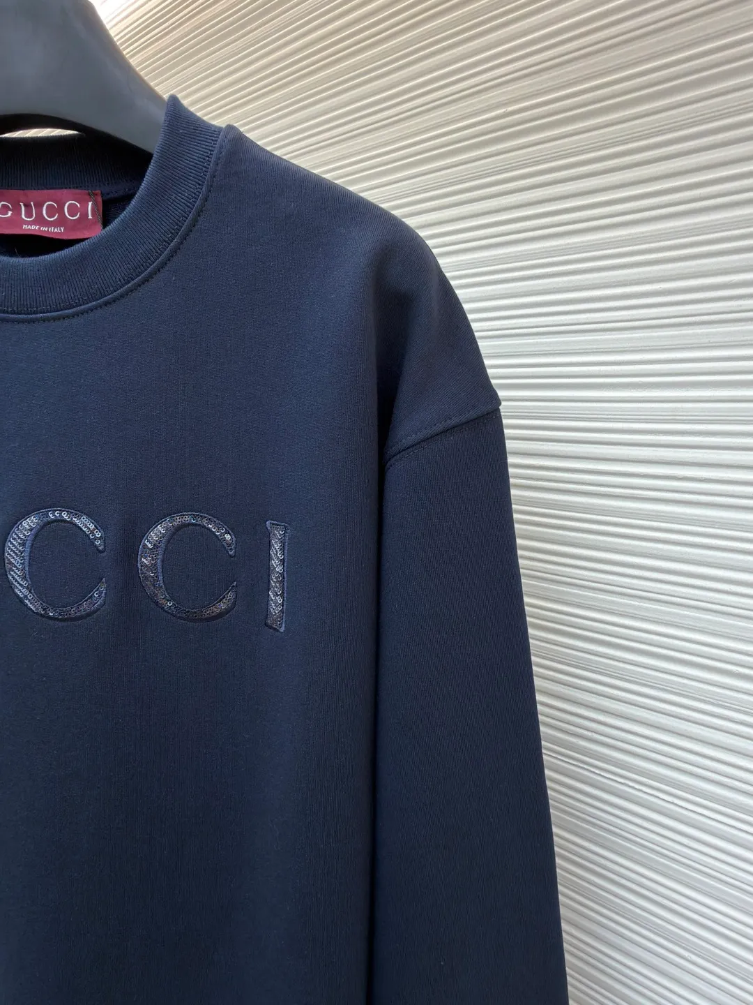 Gucci sequin round neck sweatshirt ●Original version: purchased and developed by 12060 ●Item number: 1682071-A65 ●Fabric: knitted cotton sweatshirt fabric ●Technology: double dyeing ●Color: navy blue ●Version: fitted version ●Weight: about 630 grams ●Size: XS-S-M-L ●Description: It adopts a composite structure of 26-count double yarn top layer + 10-count yarn fish scale terry bottom, with a weight of 380g/㎡; it is paired with 21-count 1x1 ribs, with a weight of 470g, and is used for the collar, cuffs and hem, ensuring the ultimate thickness, stiffness and deformation resistance of these key parts. The 26-count double yarn forms a smooth, delicate and strong outer surface of the fabric, ensuring good appearance and color fastness; the 10-count fish scale terry bottom is woven to form a unique fish scale-shaped coil. After being raised or fleeced, a layer of extremely rich, dense and unique texture is formed on the inside of the fabric. The sweatshirt combines a crisp and skeletal feel on the outside with an extremely warm and soft feel on the inside. A composite embroidery process that combines tiny sequins with embroidery thread. While the pattern is being embroidered on a computer embroidery machine, pieces of sequins are accurately positioned on the pattern through special devices or pre-arrangements, and their edges are fixed with embroidery thread. Navy blue, as the main color, is a deep, calm and classic color. It provides an excellent dark background for the sequin embroidery, making the luster of the sequins more prominent. The matte, slightly velvety texture of the fabric and the smooth, shiny sequins create a dual tactile and visual contrast. Instantly enhance the gorgeousness and visual impact of a single product, making it highly recognizable. The overall wiring is straight and delicate, the fabric is comfortable and soft, and the color is consistent without color difference. It can be matched with the same style to create a fashionable look and control various occasions. Customized accessories, complete with three standards, same style for men and women!