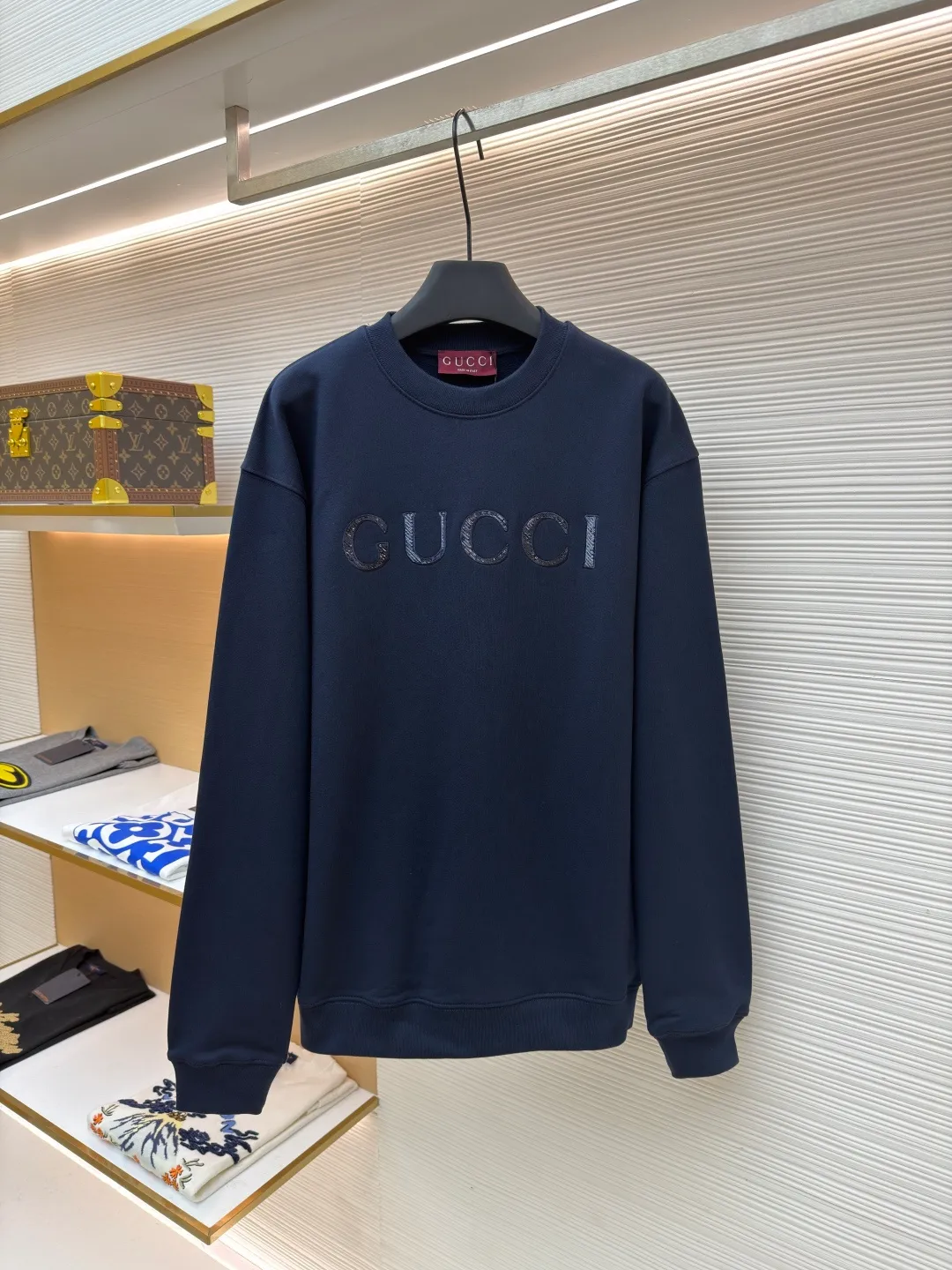 Gucci sequin round neck sweatshirt ●Original version: purchased and developed by 12060 ●Item number: 1682071-A65 ●Fabric: knitted cotton sweatshirt fabric ●Technology: double dyeing ●Color: navy blue ●Version: fitted version ●Weight: about 630 grams ●Size: XS-S-M-L ●Description: It adopts a composite structure of 26-count double yarn top layer + 10-count yarn fish scale terry bottom, with a weight of 380g/㎡; it is paired with 21-count 1x1 ribs, with a weight of 470g, and is used for the collar, cuffs and hem, ensuring the ultimate thickness, stiffness and deformation resistance of these key parts. The 26-count double yarn forms a smooth, delicate and strong outer surface of the fabric, ensuring good appearance and color fastness; the 10-count fish scale terry bottom is woven to form a unique fish scale-shaped coil. After being raised or fleeced, a layer of extremely rich, dense and unique texture is formed on the inside of the fabric. The sweatshirt combines a crisp and skeletal feel on the outside with an extremely warm and soft feel on the inside. A composite embroidery process that combines tiny sequins with embroidery thread. While the pattern is being embroidered on a computer embroidery machine, pieces of sequins are accurately positioned on the pattern through special devices or pre-arrangements, and their edges are fixed with embroidery thread. Navy blue, as the main color, is a deep, calm and classic color. It provides an excellent dark background for the sequin embroidery, making the luster of the sequins more prominent. The matte, slightly velvety texture of the fabric and the smooth, shiny sequins create a dual tactile and visual contrast. Instantly enhance the gorgeousness and visual impact of a single product, making it highly recognizable. The overall wiring is straight and delicate, the fabric is comfortable and soft, and the color is consistent without color difference. It can be matched with the same style to create a fashionable look and control various occasions. Customized accessories, complete with three standards, same style for men and women!