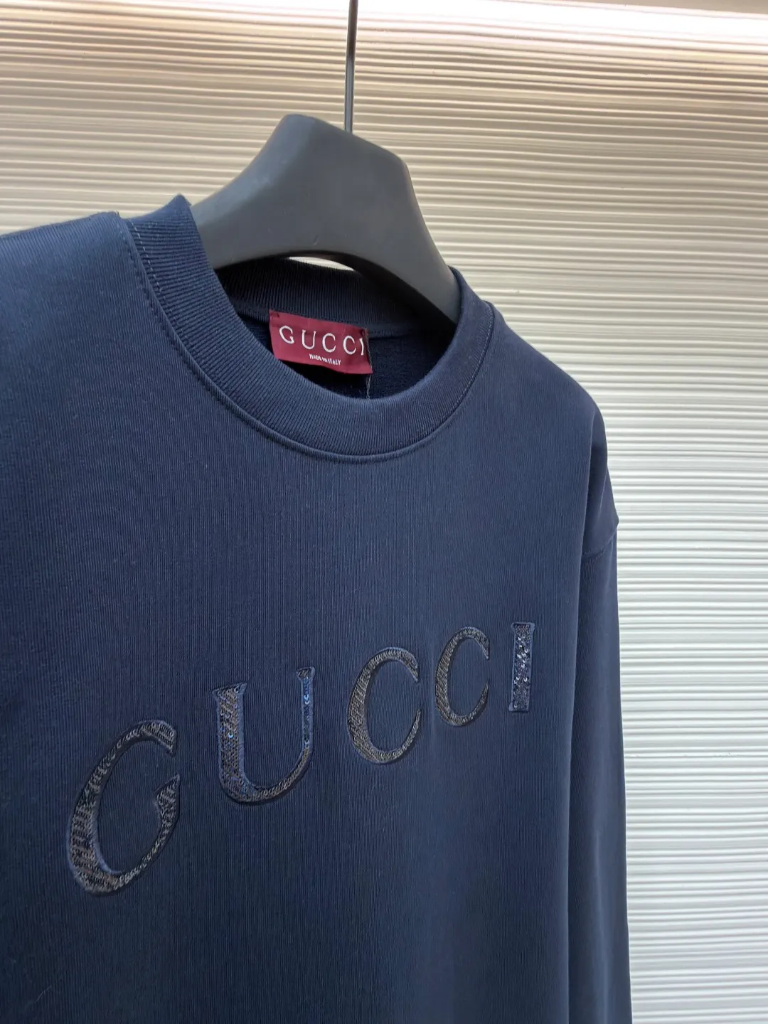 Gucci sequin round neck sweatshirt ●Original version: purchased and developed by 12060 ●Item number: 1682071-A65 ●Fabric: knitted cotton sweatshirt fabric ●Technology: double dyeing ●Color: navy blue ●Version: fitted version ●Weight: about 630 grams ●Size: XS-S-M-L ●Description: It adopts a composite structure of 26-count double yarn top layer + 10-count yarn fish scale terry bottom, with a weight of 380g/㎡; it is paired with 21-count 1x1 ribs, with a weight of 470g, and is used for the collar, cuffs and hem, ensuring the ultimate thickness, stiffness and deformation resistance of these key parts. The 26-count double yarn forms a smooth, delicate and strong outer surface of the fabric, ensuring good appearance and color fastness; the 10-count fish scale terry bottom is woven to form a unique fish scale-shaped coil. After being raised or fleeced, a layer of extremely rich, dense and unique texture is formed on the inside of the fabric. The sweatshirt combines a crisp and skeletal feel on the outside with an extremely warm and soft feel on the inside. A composite embroidery process that combines tiny sequins with embroidery thread. While the pattern is being embroidered on a computer embroidery machine, pieces of sequins are accurately positioned on the pattern through special devices or pre-arrangements, and their edges are fixed with embroidery thread. Navy blue, as the main color, is a deep, calm and classic color. It provides an excellent dark background for the sequin embroidery, making the luster of the sequins more prominent. The matte, slightly velvety texture of the fabric and the smooth, shiny sequins create a dual tactile and visual contrast. Instantly enhance the gorgeousness and visual impact of a single product, making it highly recognizable. The overall wiring is straight and delicate, the fabric is comfortable and soft, and the color is consistent without color difference. It can be matched with the same style to create a fashionable look and control various occasions. Customized accessories, complete with three standards, same style for men and women!