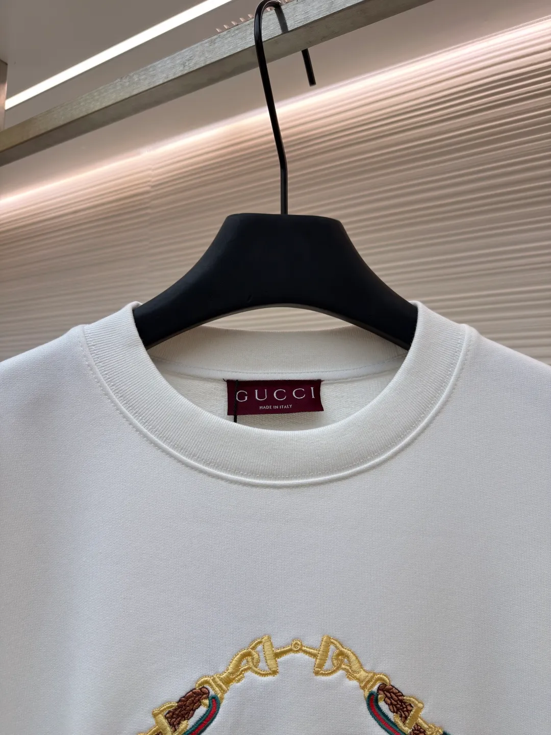 Gucci Bridle Web Round Neck Sweater ●Item No.: 1682279-A65 ●Material: 100% cotton ●Technology: Embroidery ●Color: White ●Version: Fitted ●Weight: about 645 grams ●Size: XS-S-M-L ●Description: This Gucci sweatshirt is made of high-weight combed cotton fabric. The fabric is tight and elastic, which can effectively maintain the stiffness and wearing comfort. The double G logo on the front adopts multi-layer embroidery technology, with gold thread to outline the outline, red and green velvet thread to fill the texture, and metallic chain stripe pattern appliqué. The stitches are fine and even, and each embroidery is precisely positioned to form a three-dimensional contrast with the fabric texture. The body is cut according to the loose shoulder design, and the shoulder line splicing adopts overlock stitching technology to reduce friction when wearing; the cuffs and hem are edged with ribs of the same color, which has long-lasting elasticity and is not easy to loosen. Sizes from XS to L are all standardized plate making, with increasing gradients in dimensions such as garment length and shoulder width. The stitching process uses a combination of flat seams and overlock seams to ensure the firmness of the garments and the exquisiteness of details. The overall craftsmanship combines the brand's iconic design with practical wearing performance. The overall wiring is straight and delicate, the fabric is comfortable and soft, and the color is consistent without color difference. It can be matched with the same style to create a fashionable look and control various occasions. Customized accessories, complete with three standards, same style for men and women!