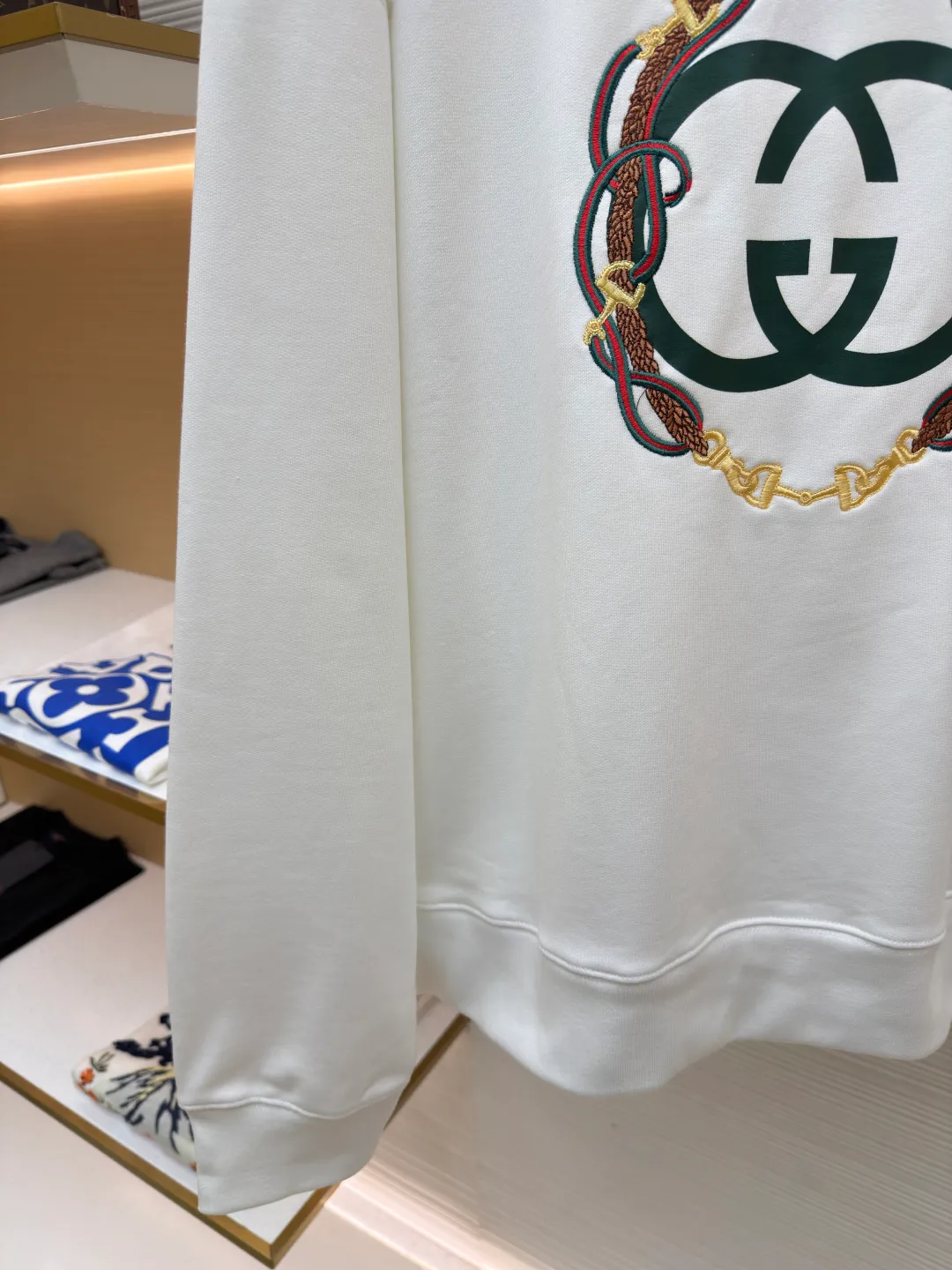 Gucci Bridle Web Round Neck Sweater ●Item No.: 1682279-A65 ●Material: 100% cotton ●Technology: Embroidery ●Color: White ●Version: Fitted ●Weight: about 645 grams ●Size: XS-S-M-L ●Description: This Gucci sweatshirt is made of high-weight combed cotton fabric. The fabric is tight and elastic, which can effectively maintain the stiffness and wearing comfort. The double G logo on the front adopts multi-layer embroidery technology, with gold thread to outline the outline, red and green velvet thread to fill the texture, and metallic chain stripe pattern appliqué. The stitches are fine and even, and each embroidery is precisely positioned to form a three-dimensional contrast with the fabric texture. The body is cut according to the loose shoulder design, and the shoulder line splicing adopts overlock stitching technology to reduce friction when wearing; the cuffs and hem are edged with ribs of the same color, which has long-lasting elasticity and is not easy to loosen. Sizes from XS to L are all standardized plate making, with increasing gradients in dimensions such as garment length and shoulder width. The stitching process uses a combination of flat seams and overlock seams to ensure the firmness of the garments and the exquisiteness of details. The overall craftsmanship combines the brand's iconic design with practical wearing performance. The overall wiring is straight and delicate, the fabric is comfortable and soft, and the color is consistent without color difference. It can be matched with the same style to create a fashionable look and control various occasions. Customized accessories, complete with three standards, same style for men and women!