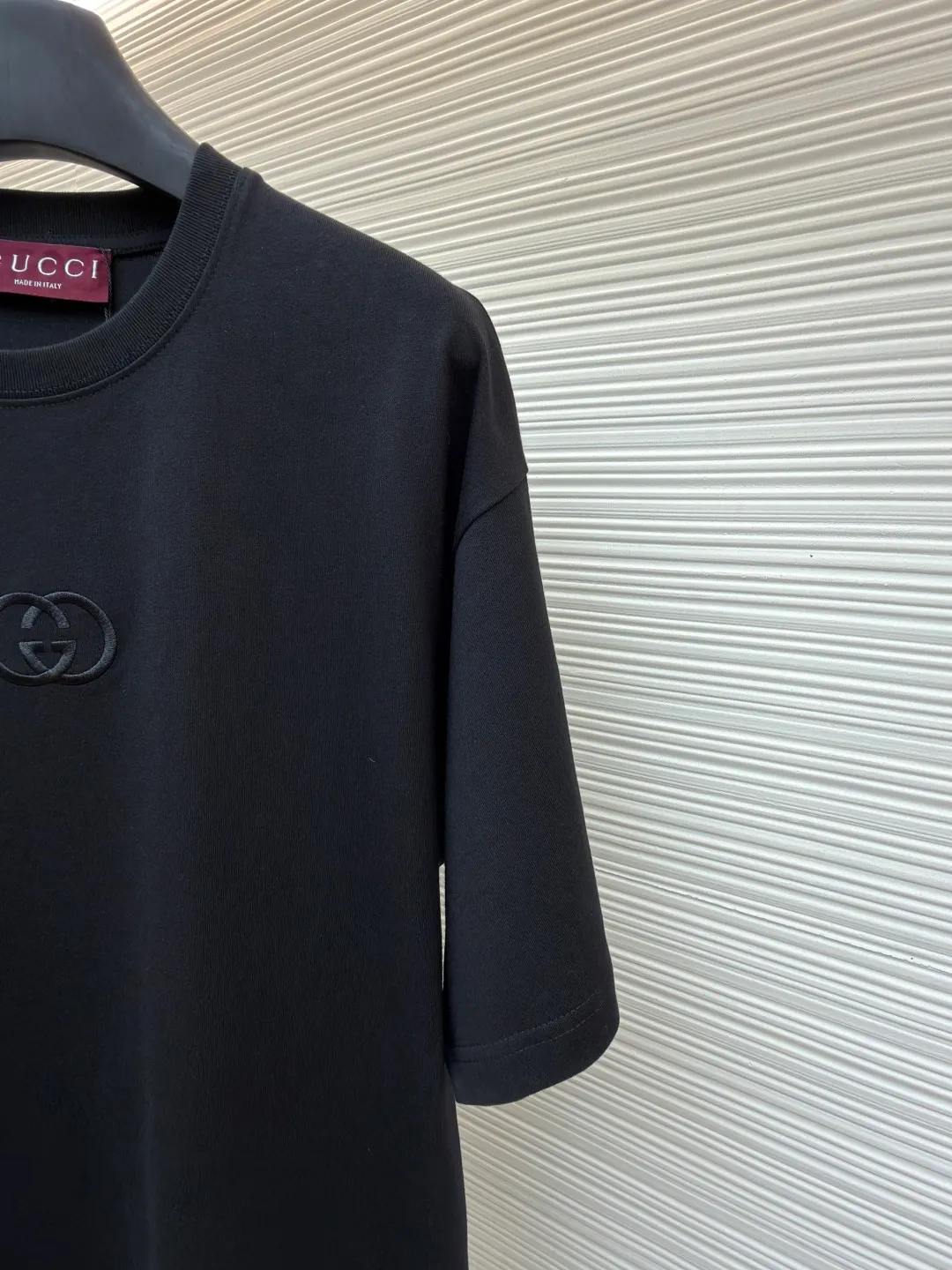 Gucci Double G embroidered round neck short sleeves ●Original version: purchased and developed by 2977 ●Item number: 1682217-A00 ●Fabric: fine velvet knitted cotton fabric ●Technology: embroidery production ●Color: black ●Version: fitted version ●Weight: about 280 grams ●Size: XS-S-M-L ●Description: Made of 15S special woven compact cotton fine velvet knitted fabric with a weight of 230g/㎡; paired with 32S high count and high weight 1x1 rib, with a weight of 340g/㎡. Ribbing is used on the collar to ensure excellent elastic recovery and deformation resistance of the collar. The fabric uses compact spinning technology to effectively reduce yarn hairiness, making the fabric structure tighter, the surface smoother, and the pilling resistance better. The weight of 230g is medium to heavy, which gives the T-shirt good stiffness and drape, and is not easy to collapse, ensuring the texture of high-end ready-to-wear. The fine velvet knitted fabric has been lightly brushed or raised, giving it a softer, waxier skin-friendly feel than ordinary plain cotton. Three-dimensional stitch embroidery is an embroidery process that uses high-density linear stitches to be closely arranged to form raised lines. The core is to use thicker embroidery thread, and the stitches are continuous and even without gaps. It naturally produces a raised height of 1-2 mm, making the edges of the pattern clear and sharp, and the touch feeling full and solid. The overall wiring is straight and delicate, the fabric is comfortable and soft, and the color is consistent without color difference. It can be matched with the same style to create a fashionable look and control various occasions. Customized accessories, complete with three standards, same style for men and women!
