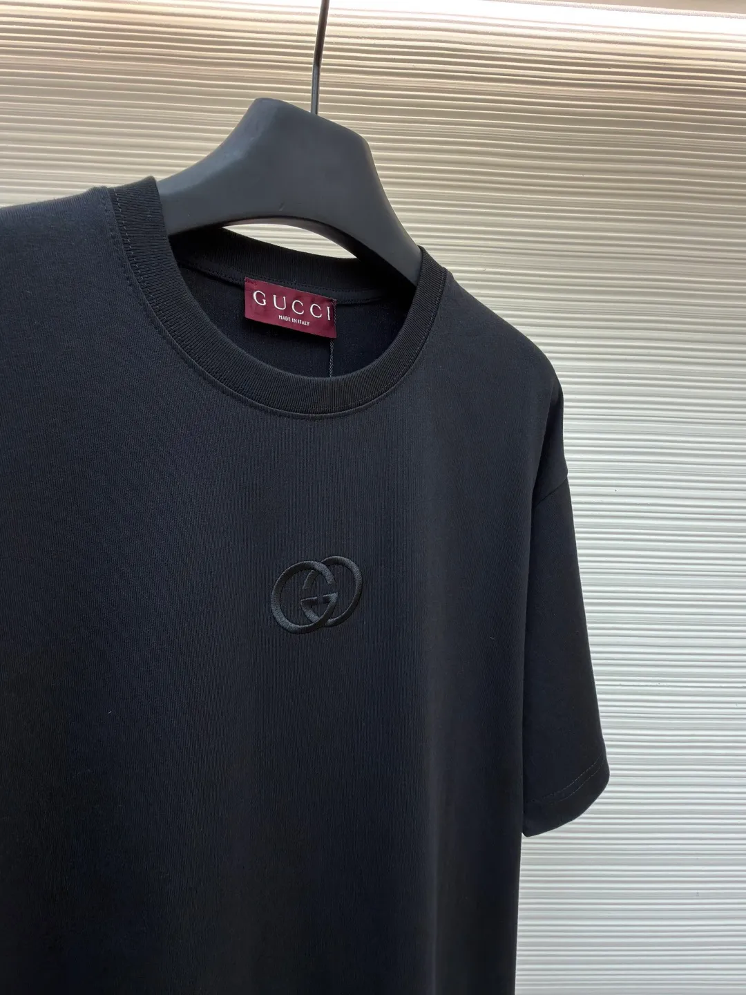Gucci Double G embroidered round neck short sleeves ●Original version: purchased and developed by 2977 ●Item number: 1682217-A00 ●Fabric: fine velvet knitted cotton fabric ●Technology: embroidery production ●Color: black ●Version: fitted version ●Weight: about 280 grams ●Size: XS-S-M-L ●Description: Made of 15S special woven compact cotton fine velvet knitted fabric with a weight of 230g/㎡; paired with 32S high count and high weight 1x1 rib, with a weight of 340g/㎡. Ribbing is used on the collar to ensure excellent elastic recovery and deformation resistance of the collar. The fabric uses compact spinning technology to effectively reduce yarn hairiness, making the fabric structure tighter, the surface smoother, and the pilling resistance better. The weight of 230g is medium to heavy, which gives the T-shirt good stiffness and drape, and is not easy to collapse, ensuring the texture of high-end ready-to-wear. The fine velvet knitted fabric has been lightly brushed or raised, giving it a softer, waxier skin-friendly feel than ordinary plain cotton. Three-dimensional stitch embroidery is an embroidery process that uses high-density linear stitches to be closely arranged to form raised lines. The core is to use thicker embroidery thread, and the stitches are continuous and even without gaps. It naturally produces a raised height of 1-2 mm, making the edges of the pattern clear and sharp, and the touch feeling full and solid. The overall wiring is straight and delicate, the fabric is comfortable and soft, and the color is consistent without color difference. It can be matched with the same style to create a fashionable look and control various occasions. Customized accessories, complete with three standards, same style for men and women!