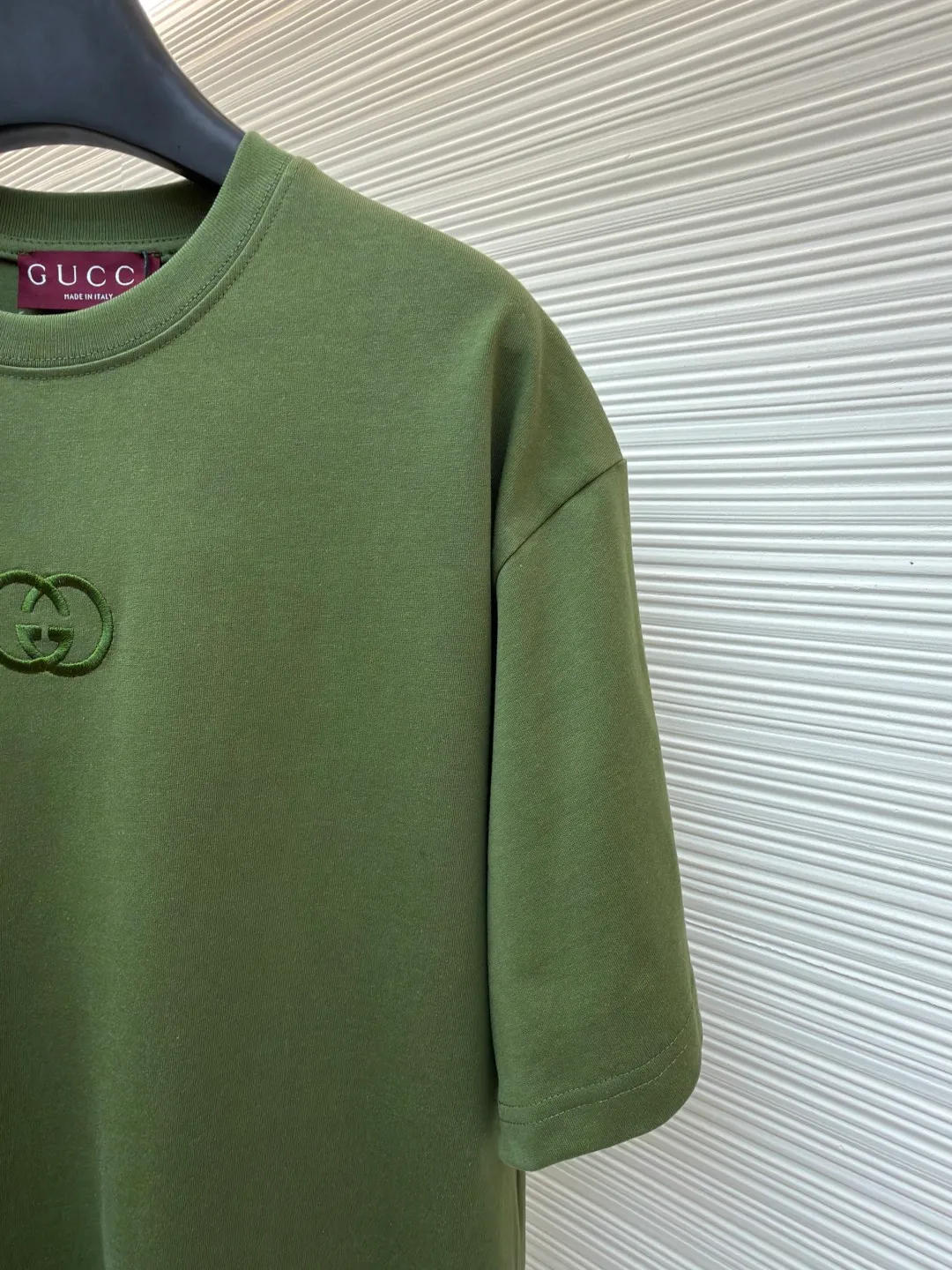 Gucci Double G embroidered round neck short sleeves ●Original version: Purchased and developed for 5300 ●Item number: 1682499-X90 ●Fabric: fine velvet knitted cotton fabric ●Technology: embroidery production ●Color: green ●Version: fitted version ●Weight: about 290 grams ●Size: S-M-L-XL ●Description: Made of 15S special woven compact cotton fine velvet knitted fabric with a weight of 230g/㎡; paired with 32S high count and high weight 1x1 rib, with a weight of 340g/㎡. Ribbing is used on the collar to ensure excellent elastic recovery and deformation resistance of the collar. The fabric uses compact spinning technology to effectively reduce yarn hairiness, making the fabric structure tighter, the surface smoother, and the pilling resistance better. The weight of 230g is medium to heavy, which gives the T-shirt good stiffness and drape, and is not easy to collapse, ensuring the texture of high-end ready-to-wear. The fine velvet knitted fabric has been lightly brushed or raised, giving it a softer, waxier skin-friendly feel than ordinary plain cotton. Three-dimensional stitch embroidery is an embroidery process that uses high-density linear stitches to be closely arranged to form raised lines. The core is to use thicker embroidery thread, and the stitches are continuous and even without gaps. It naturally produces a raised height of 1-2 mm, making the edges of the pattern clear and sharp, and the touch feeling full and solid. The overall wiring is straight and delicate, the fabric is comfortable and soft, and the color is consistent without color difference. It can be matched with the same style to create a fashionable look and control various occasions. Customized accessories, complete with three standards, same style for men and women!