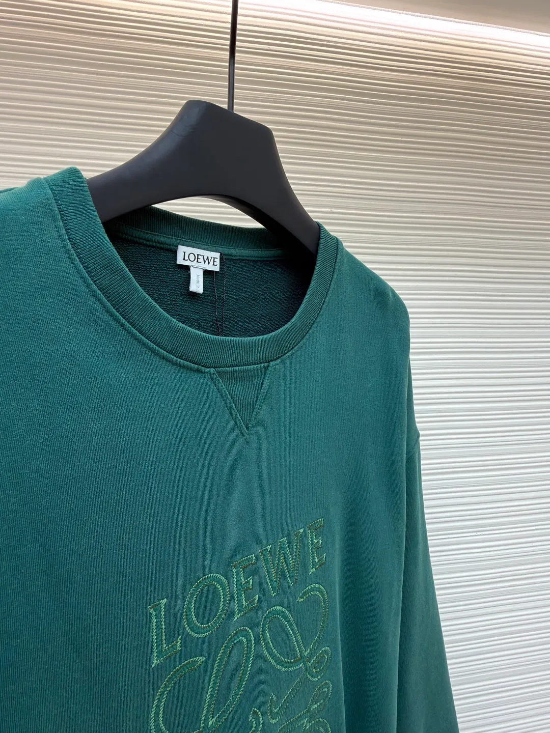Loewe zigzag thread appliqué round neck sweatshirt ●Original version: Purchased and developed by 3621 ●Item number: 1680967-A90 ●Fabric: Fleece fabric ●Technology: Laser cutting appliqué production ●Version: Fitted version ●Weight: about 635g ●Size: 2*2 thread, 470g. The fish scale bottom fabric forms a fish scale pattern through a specific weaving process, and the plates are arranged and interwoven according to the warp and weft patterns and shapes to ensure clear texture and excellent texture. The fabric has been carefully produced and processed, and has good durability, lightness, softness, and good breathability. The edge-strengthened branches of the appliqué embroidery add a rough industrial look by imitating zigzag-shaped stitches. The appliqué stitches are in the form of trapezoidal zigzags, resembling interlaced canine teeth; emphasizing high stitch density and sharp turns, like saw blade cutting marks. Trim the seam allowance and cut off excess fabric along the dogtooth stitches to retain the jagged three-dimensional effect. After the garment is made, it is made through frying process. The garment is dyed, washed and aged using new environmentally friendly technology. Fabrics are dyed using a stone grinding method, and the garments are continuously immersed in dye and tumbled. After frying the sand, the fabric fades slightly, changing the color of the original fabric to show a nostalgic color with different shades of light and dark. The neckline adopts a structural feature formed by a V-shaped rib weaving method, which visually has a unique sense of line and extensibility. The rib structure itself has good elasticity and stretchability; inserts are added to the shoulder seams to increase the service life. The neckline, hem, and cuffs are all spliced ​​with double-needle threading. The body and sleeves are structurally split and quilted. The fabric material has high ductility and no sense of restraint. The overall wiring is straight and delicate, the fabric is comfortable and soft, and the color is consistent without color difference. It can be matched with the same style to create a fashionable look and control various occasions. Customized accessories, complete with three standards, same style for men and women!