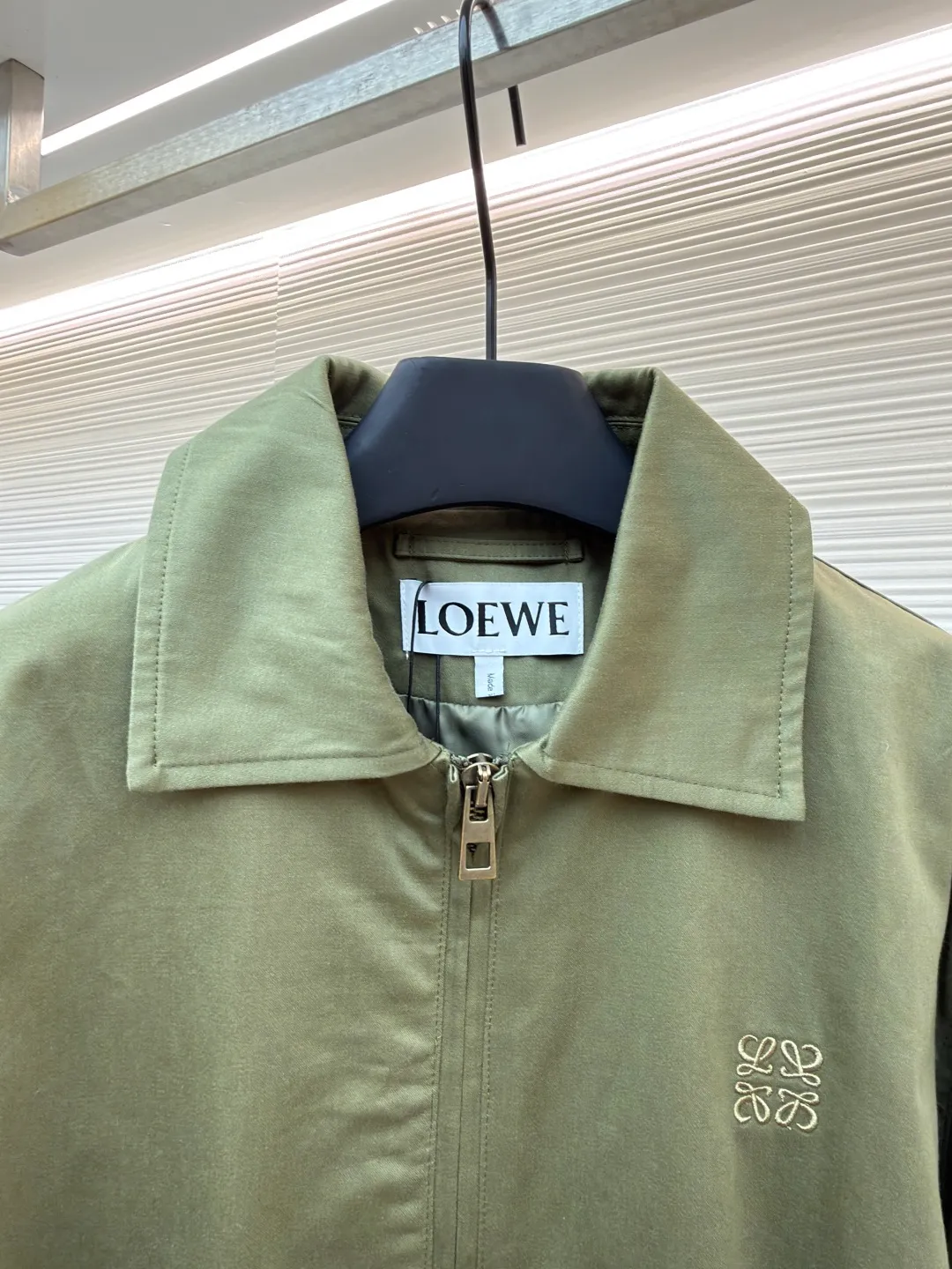 Loewe Army Green Trimmed Jacket ●Original version: Purchased and developed for 20900 ●Item number: 1682098-B40 ●Fabric: High weight dyed cotton satin fabric ●Technology: Leather patch production ●Color: Military green ●Version: Fitted version ●Weight: about 745 grams ●Size: 46-48-50-52 ●Description: Made of 100% pure cotton cloth, the fabric is dyed in the original color. The leather label is made of real cowhide composite, and the surface is stamped with gold powder to create the brand logo. The waist belt is made of multi-layer composite, and the oil edge design presents a different visual effect. Medium weight garment-dyed cotton satin jacket with gathered front and decorative contrasting belt. * Regular fit, standard length * Classic collar * Front zip closure, button cuffs * Seamed pockets, internal welt pockets * Fully lined * Anagram embroidery on chest, LOEWE embossed leather patch on back. The overall wiring is straight and delicate, the fabric is comfortable and soft, and the color is consistent without color difference. It can be matched with the same style to create a fashionable look and control various occasions. Customized accessories, complete with three standards, same style for men and women!