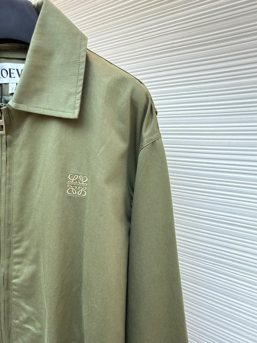 Loewe Army Green Trimmed Jacket ●Original version: Purchased and developed for 20900 ●Item number: 1682098-B40 ●Fabric: High weight dyed cotton satin fabric ●Technology: Leather patch production ●Color: Military green ●Version: Fitted version ●Weight: about 745 grams ●Size: 46-48-50-52 ●Description: Made of 100% pure cotton cloth, the fabric is dyed in the original color. The leather label is made of real cowhide composite, and the surface is stamped with gold powder to create the brand logo. The waist belt is made of multi-layer composite, and the oil edge design presents a different visual effect. Medium weight garment-dyed cotton satin jacket with gathered front and decorative contrasting belt. * Regular fit, standard length * Classic collar * Front zip closure, button cuffs * Seamed pockets, internal welt pockets * Fully lined * Anagram embroidery on chest, LOEWE embossed leather patch on back. The overall wiring is straight and delicate, the fabric is comfortable and soft, and the color is consistent without color difference. It can be matched with the same style to create a fashionable look and control various occasions. Customized accessories, complete with three standards, same style for men and women!