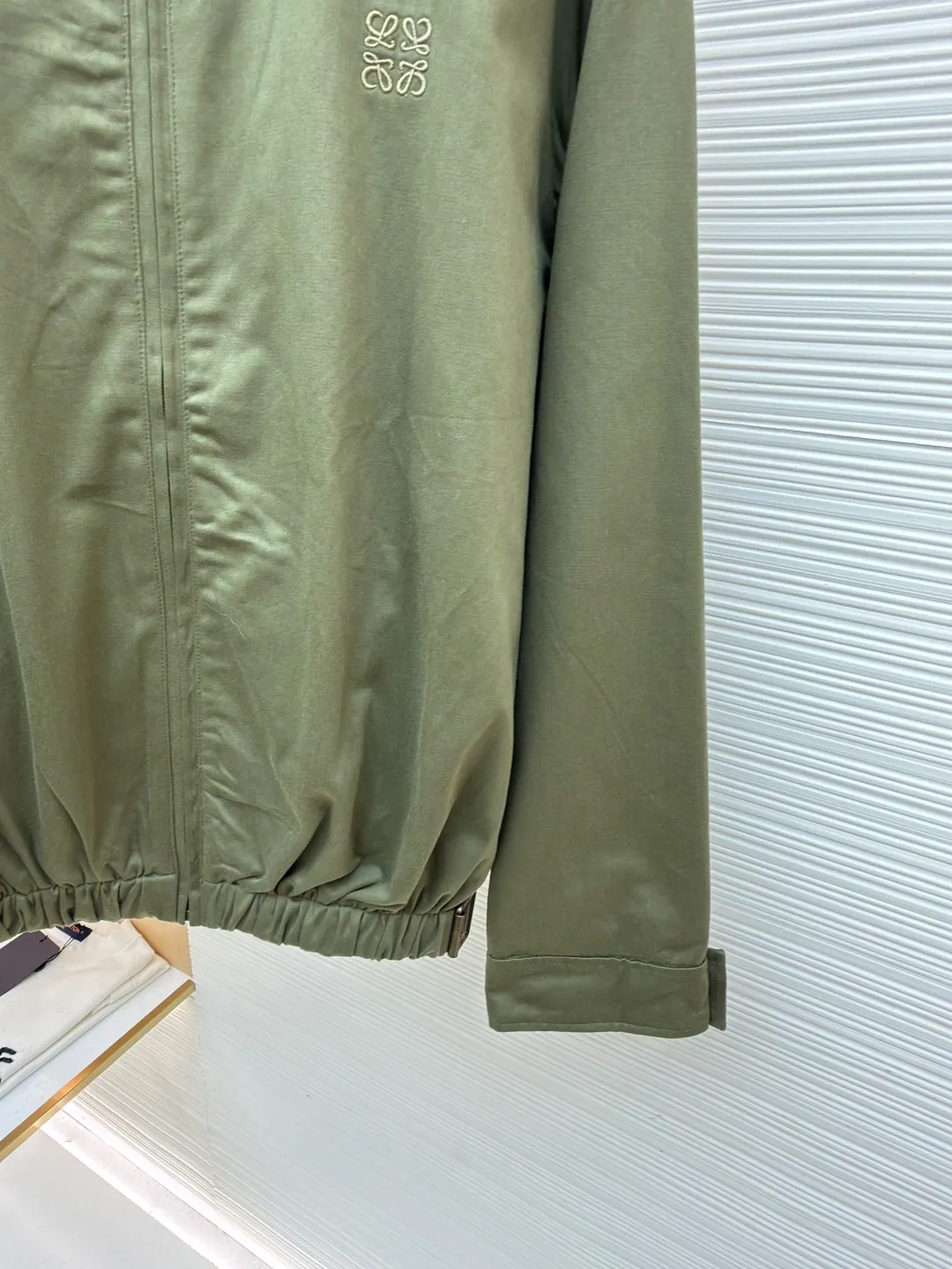 Loewe Army Green Trimmed Jacket ●Original version: Purchased and developed for 20900 ●Item number: 1682098-B40 ●Fabric: High weight dyed cotton satin fabric ●Technology: Leather patch production ●Color: Military green ●Version: Fitted version ●Weight: about 745 grams ●Size: 46-48-50-52 ●Description: Made of 100% pure cotton cloth, the fabric is dyed in the original color. The leather label is made of real cowhide composite, and the surface is stamped with gold powder to create the brand logo. The waist belt is made of multi-layer composite, and the oil edge design presents a different visual effect. Medium weight garment-dyed cotton satin jacket with gathered front and decorative contrasting belt. * Regular fit, standard length * Classic collar * Front zip closure, button cuffs * Seamed pockets, internal welt pockets * Fully lined * Anagram embroidery on chest, LOEWE embossed leather patch on back. The overall wiring is straight and delicate, the fabric is comfortable and soft, and the color is consistent without color difference. It can be matched with the same style to create a fashionable look and control various occasions. Customized accessories, complete with three standards, same style for men and women!