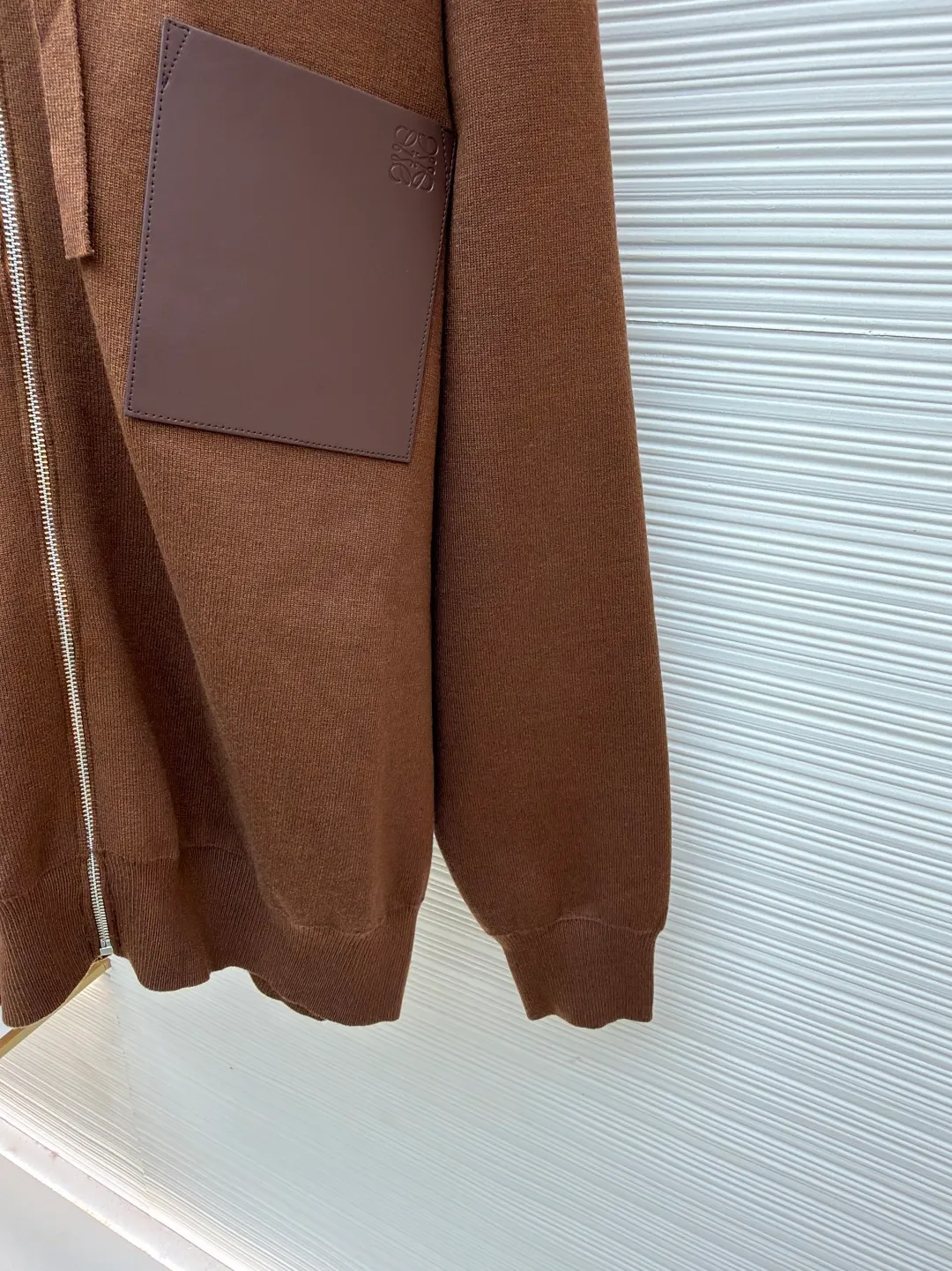 Loewe leather label pocket knitted zipper hoodie ●Original version: purchased and developed for 15900 ●Item number: 1681812-B15 ●Fabric: wool blended fabric ●Technology: knitted patch production ●Color: brown ●Version: fitted version ●Weight: about 1040 grams ●Size: S-M-L-XL ●Description: Made of 55% merino wool and woven with a 14-needle imported machine. The entire garment weighs about 960-1000 grams. The upper body shape is very three-dimensional. The thermal insulation effect is also very good when worn outside. The leather label is made of double-layer composite imitation cowhide, and the process adopts three-dimensional relief embossing technology, and the Anagram icon is embossed with high temperature. Laser positioning and wiring, each piece of clothing passes multi-layer quality inspection before being shipped. The zippers are made of No. 5 bright white electroplated zippers, the LOEWE brand logo is electroplated and engraved on the sides, and the pull teeth are made of Euler electroplated teeth. Garment washing - removal of wool impurities - color fixation - fixed fit medium weight wool hooded sweatshirt. *Regular fit, standard length*Double side seams*Hooded collar*Leather chest patch pocket*Front zip closure*Ribbed cuffs and hem*Chest pocket trim. The overall wiring is straight and delicate, the fabric is comfortable and soft, and the color is consistent without color difference. It can be matched with the same style to create a fashionable look and control various occasions. Customized accessories, complete with three standards, same style for men and women!