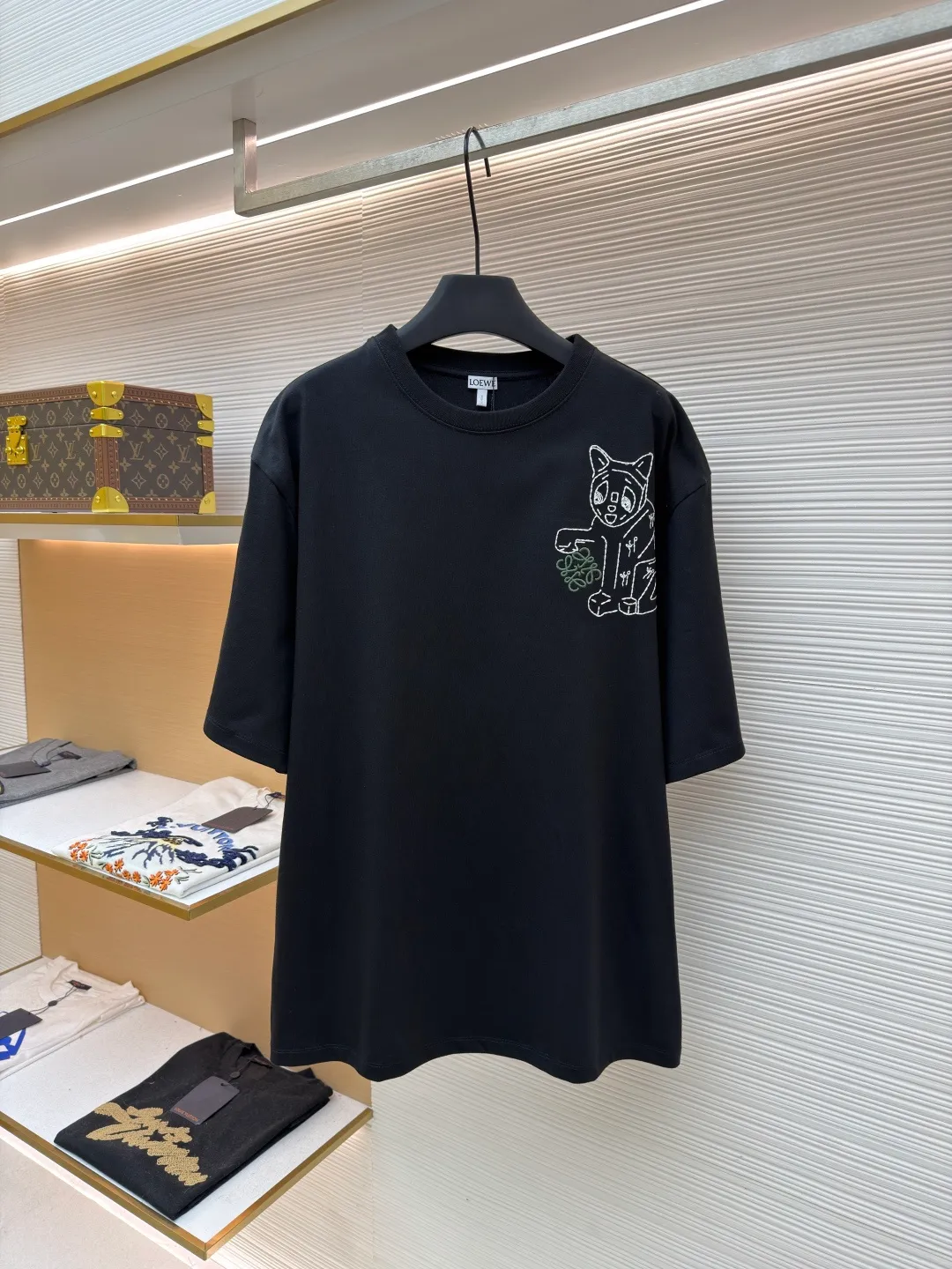 Loewe Cat Line Pattern Round Neck Short Sleeve ●Original version: Purchased and developed at 4330 ●Item number: 1681867-X85 ●Material: combed cotton fabric ●Technology: embroidery production ●Color: black ●Version: fitted version ●Weight: about 295 grams ●Size: XS-S-M-L ●Description: Made of 15S fine cotton plain fabric, 230g; with 32S double yarn thread, 300g. Plain weave fabric made from combed cotton fibers has a more orderly arrangement and higher density than ordinary cotton, so it has better texture and luster. 15S fine cotton plain fabric is a high-quality cotton fabric with the characteristics of softness, comfort, good breathability, and good durability. Anagram Embroidery Lucky Cat: The rice grain line embroidery process uses special ultra-fine embroidery thread and high-density stitching to create a pattern outline as delicate and continuous as grains. Its core feature lies in the precise arrangement of ultra-fine stitches, which require 12-15 stitches per centimeter to form full lines, and the edges present a handmade micro-waving effect. The fabric achieves a stroke-like gradient of thickness and flow. The overall pattern is light, breathable and smooth to the touch. It looks like a line outline from a distance, but the texture of interwoven fibers can be seen up close. It is especially suitable for expressing delicate details such as logo outlines and geometric borders. Anagram embroidery: Using three-dimensional embroidery technology, the logo clearly restores the spacing curve. The mercerized embroidery thread with luster is selected, combined with complex embroidery needlework and fine detail processing to create a three-dimensional relief embroidery effect. Classic trademark letter design, fine embroidery and dense stitching, clear font and strong sense of lines and three-dimensionality. The overall wiring is straight and delicate, the fabric is comfortable and soft, and the color is consistent without color difference. It can be matched with the same style to create a fashionable look and control various occasions. Customized accessories, complete with three standards, same style for men and women!