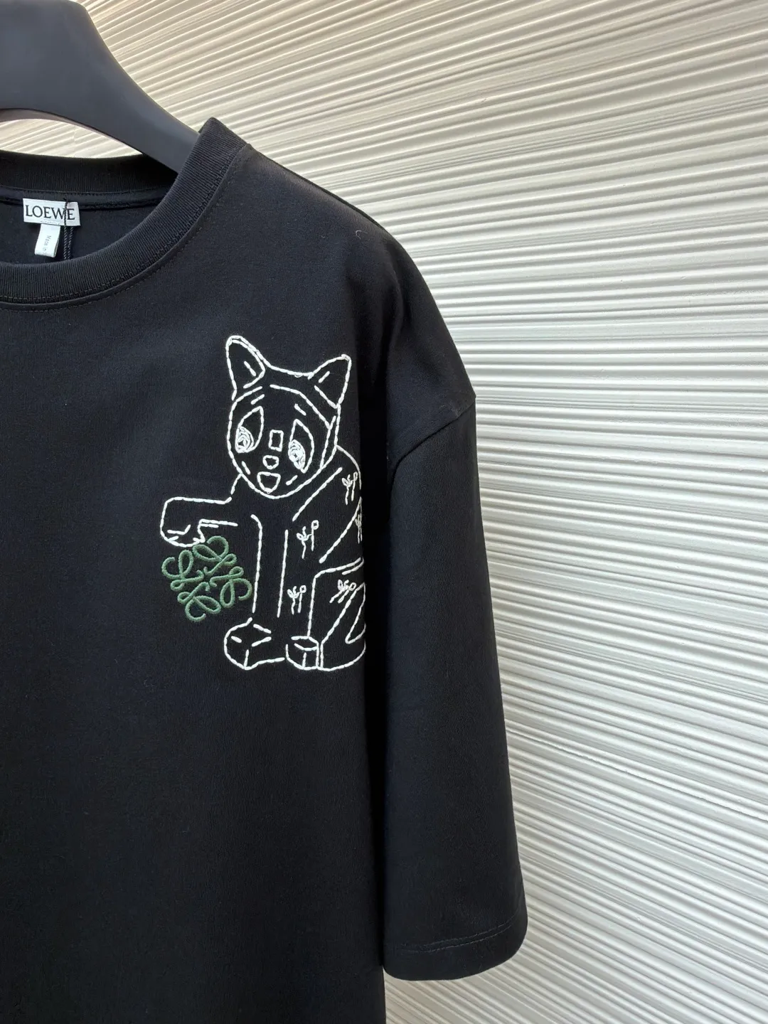 Loewe Cat Line Pattern Round Neck Short Sleeve ●Original version: Purchased and developed at 4330 ●Item number: 1681867-X85 ●Material: combed cotton fabric ●Technology: embroidery production ●Color: black ●Version: fitted version ●Weight: about 295 grams ●Size: XS-S-M-L ●Description: Made of 15S fine cotton plain fabric, 230g; with 32S double yarn thread, 300g. Plain weave fabric made from combed cotton fibers has a more orderly arrangement and higher density than ordinary cotton, so it has better texture and luster. 15S fine cotton plain fabric is a high-quality cotton fabric with the characteristics of softness, comfort, good breathability, and good durability. Anagram Embroidery Lucky Cat: The rice grain line embroidery process uses special ultra-fine embroidery thread and high-density stitching to create a pattern outline as delicate and continuous as grains. Its core feature lies in the precise arrangement of ultra-fine stitches, which require 12-15 stitches per centimeter to form full lines, and the edges present a handmade micro-waving effect. The fabric achieves a stroke-like gradient of thickness and flow. The overall pattern is light, breathable and smooth to the touch. It looks like a line outline from a distance, but the texture of interwoven fibers can be seen up close. It is especially suitable for expressing delicate details such as logo outlines and geometric borders. Anagram embroidery: Using three-dimensional embroidery technology, the logo clearly restores the spacing curve. The mercerized embroidery thread with luster is selected, combined with complex embroidery needlework and fine detail processing to create a three-dimensional relief embroidery effect. Classic trademark letter design, fine embroidery and dense stitching, clear font and strong sense of lines and three-dimensionality. The overall wiring is straight and delicate, the fabric is comfortable and soft, and the color is consistent without color difference. It can be matched with the same style to create a fashionable look and control various occasions. Customized accessories, complete with three standards, same style for men and women!