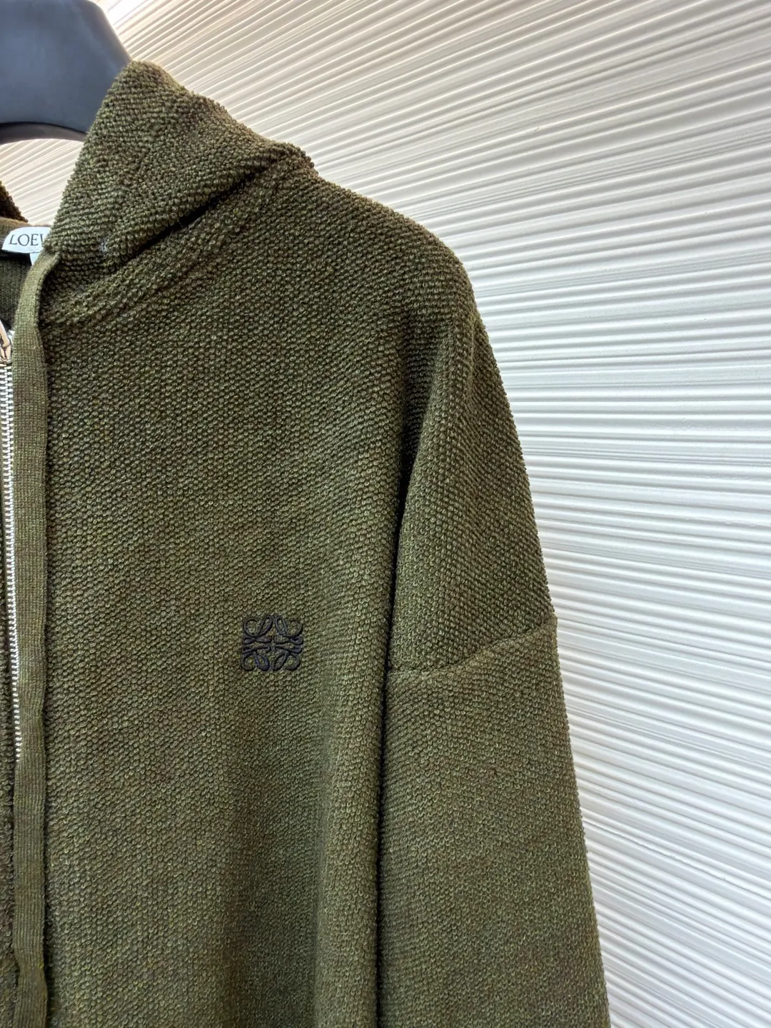 Loewe embroidered hooded zipper cardigan ●Original version: Purchased and developed by 9856 ●Item number: 1682194-B70 ●Material: wool blended fabric ●Technology: embroidery production ●Color: khaki green ●Version: Loose fit ●Weight: about 935 grams ●Size: S-M-L-XL ●Description: Selected high-quality wool as the main body, with unique terry cloth stitching technology, is a highlight of this sweatshirt. This stitching method not only gives the sweatshirt a unique texture and texture, but also demonstrates our stringent quality requirements in every detail. Every seam is tight and even, like a carefully carved work of art, which not only enhances the durability of the clothing, but also adds a unique fashion charm. Ribbed cuffs and hem are the perfect combination of classic and practical. They fit the body well, prevent cold wind from getting in, and provide excellent warmth. At the same time, the elastic properties of the ribs also ensure the comfort of wearing it and will not cause any restrictions on body movements. On the chest, the high-precision calculation system of the computer embroidery machine controls the coordinated operation of the machine head, needle bar, and thread spool. The fabric frame moves accurately in the horizontal and vertical directions to form a stitch track. The upper and lower thread tensions are adjusted to ensure that the stitches are smooth and free of floating threads, forming anagram embroidery with an error of ±0.1mm. The overall wiring is straight and delicate, the fabric is comfortable and soft, and the color is consistent without color difference. It can be matched with the same style to create a fashionable look and control various occasions. Customized accessories, complete with three standards, same style for men and women!
