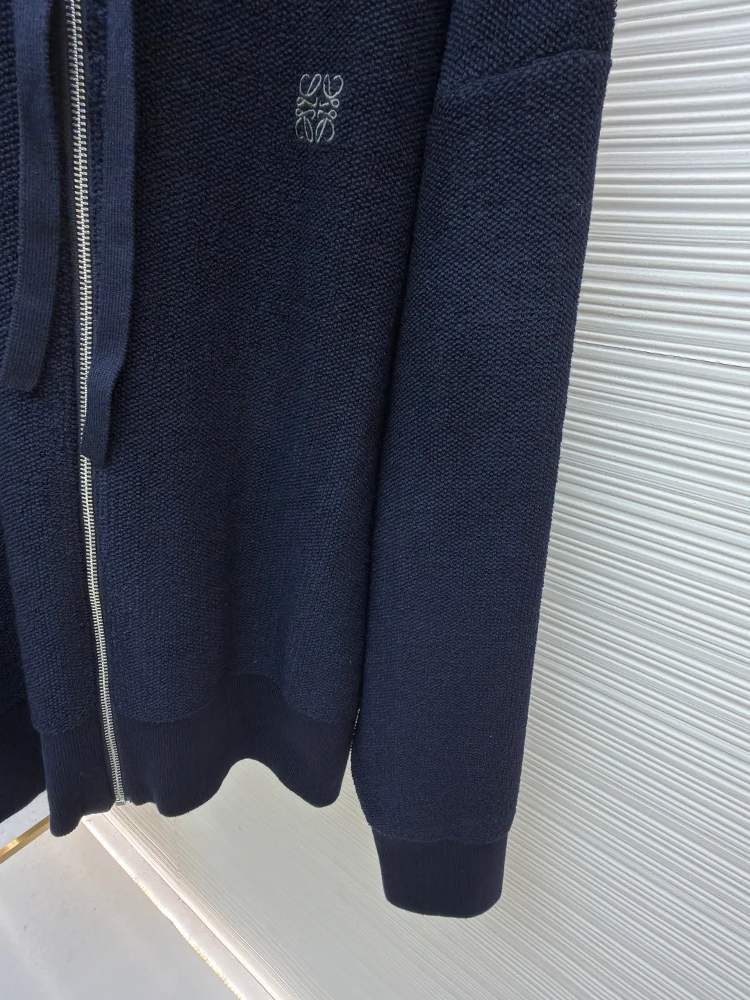 Loewe embroidered hooded zipper cardigan ●Original version: Purchased and developed by 10204 ●Item number: 1682195-B70 ●Material: wool blended fabric ●Technology: embroidery production ●Color: navy ●Version: Loose fit ●Weight: about 950 grams ●Size: S-M-L-XL ●Description: Selected high-quality wool as the main body, with unique terry cloth stitching technology, is a highlight of this sweatshirt. This stitching method not only gives the sweatshirt a unique texture and texture, but also demonstrates our stringent quality requirements in every detail. Every seam is tight and even, like a carefully carved work of art, which not only enhances the durability of the clothing, but also adds a unique fashion charm. Ribbed cuffs and hem are the perfect combination of classic and practical. They fit the body well, prevent cold wind from getting in, and provide excellent warmth. At the same time, the elastic properties of the ribs also ensure the comfort of wearing it and will not cause any restrictions on body movements. On the chest, the high-precision calculation system of the computer embroidery machine controls the coordinated operation of the machine head, needle bar, and thread spool. The fabric frame moves accurately in the horizontal and vertical directions to form a stitch track. The upper and lower thread tensions are adjusted to ensure that the stitches are smooth and free of floating threads, forming anagram embroidery with an error of ±0.1mm. The overall wiring is straight and delicate, the fabric is comfortable and soft, and the color is consistent without color difference. It can be matched with the same style to create a fashionable look and control various occasions. Customized accessories, complete with three standards, same style for men and women!