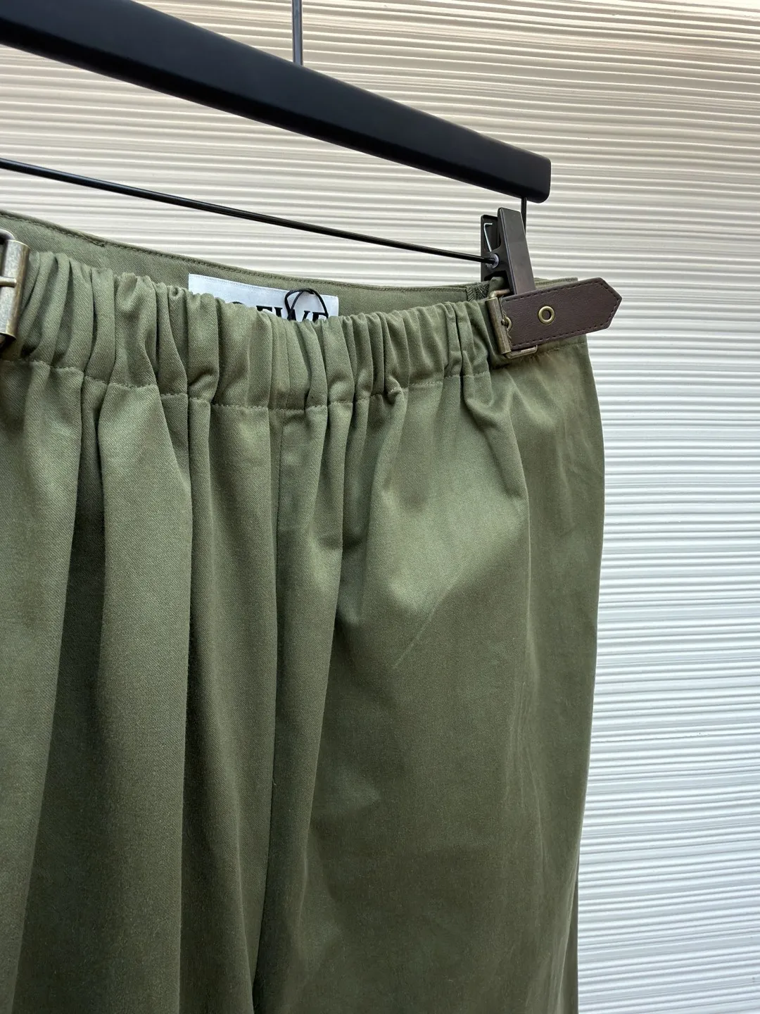 Loewe military green belt trousers ●Original version: purchased and developed by 7161 ●Item number: 1681217-B15 ●Fabric: high weight dyed cotton satin fabric ●Technology: leather patch production ●Color: military green ●Version: loose fit ●Weight: about 530 grams ●Size: 46-48-50-52 ●Description: Made of high-weight cotton satin fabric, high-weight high-temperature dyed cotton satin fabric is a high-end material with excellent texture and functionality. The core of its technology lies in the selection of high-count, long-staple cotton, and the satin weave method to minimize the interweaving points of warp and weft yarns, thereby forming a unique surface that is smooth, supple and with a faint luster. The high weight ensures that the fabric has a tight structure, is crisp and stylish, and has excellent drape and wear resistance. , "Using high-temperature and high-pressure dyeing technology in the dyeing process, the dye molecules can deeply penetrate into the core of the fiber, thereby achieving high color saturation, strong color fastness and not easy to fade. This process not only gives the fabric a rich and lasting color, but also makes it plump and soft to the touch. It also retains the natural breathability of cotton fiber, achieving a both luxurious and practical wearing experience. The contrasting color decorative belt echoes the theme of military uniforms and allows for flexible waist adjustment; the back is embossed with bronzing leather patches, which use high temperature and high pressure. The brand logo is permanently embossed on the leather and sewn onto the back of the jacket. This process makes the pattern clear and durable, becoming a low-key and powerful symbol of the brand's identity. The style adopts a regular fit and a mid-rise straight design to ensure clean lines and comfortable wearing. The front gathers are an important decorative element and provide room for movement in the functional legs. The pocket design is both practical and simple, while the rear button-stuck welt pocket enhances the sophistication of workwear style.