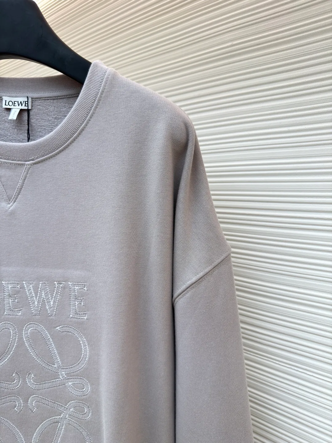 Loewe zigzag thread appliqué round neck sweatshirt ●Original version: Purchased and developed by 3621 ●Item number: 1680966-A90 ●Fabric: Fleece fabric ●Technology: Laser cutting appliqué production ●Version: Fitted version ●Weight: about 580g ●Size: 2*2 thread, 470g. The fish scale bottom fabric forms a fish scale pattern through a specific weaving process, and the plates are arranged and interwoven according to the warp and weft patterns and shapes to ensure clear texture and excellent texture. The fabric has been carefully produced and processed, and has good durability, lightness, softness, and good breathability. The edge-strengthened branches of the appliqué embroidery add a rough industrial look by imitating zigzag-shaped stitches. The appliqué stitches are in the form of trapezoidal zigzags, resembling interlaced canine teeth; emphasizing high stitch density and sharp turns, like saw blade cutting marks. Trim the seam allowance and cut off excess fabric along the dogtooth stitches to retain the jagged three-dimensional effect. After the garment is made, it is made through frying process. The garment is dyed, washed and aged using new environmentally friendly technology. Fabrics are dyed using a stone grinding method, and the garments are continuously immersed in dye and tumbled. After frying the sand, the fabric fades slightly, changing the color of the original fabric to show a nostalgic color with different shades of light and dark. The neckline adopts a structural feature formed by a V-shaped rib weaving method, which visually has a unique sense of line and extensibility. The rib structure itself has good elasticity and stretchability; inserts are added to the shoulder seams to increase the service life. The neckline, hem, and cuffs are all spliced ​​with double-needle threading. The body and sleeves are structurally split and quilted. The fabric material has high ductility and no sense of restraint. The overall wiring is straight and delicate, the fabric is comfortable and soft, and the color is consistent without color difference. It can be matched with the same style to create a fashionable look and control various occasions. Customized accessories, complete with three standards, same style for men and women!