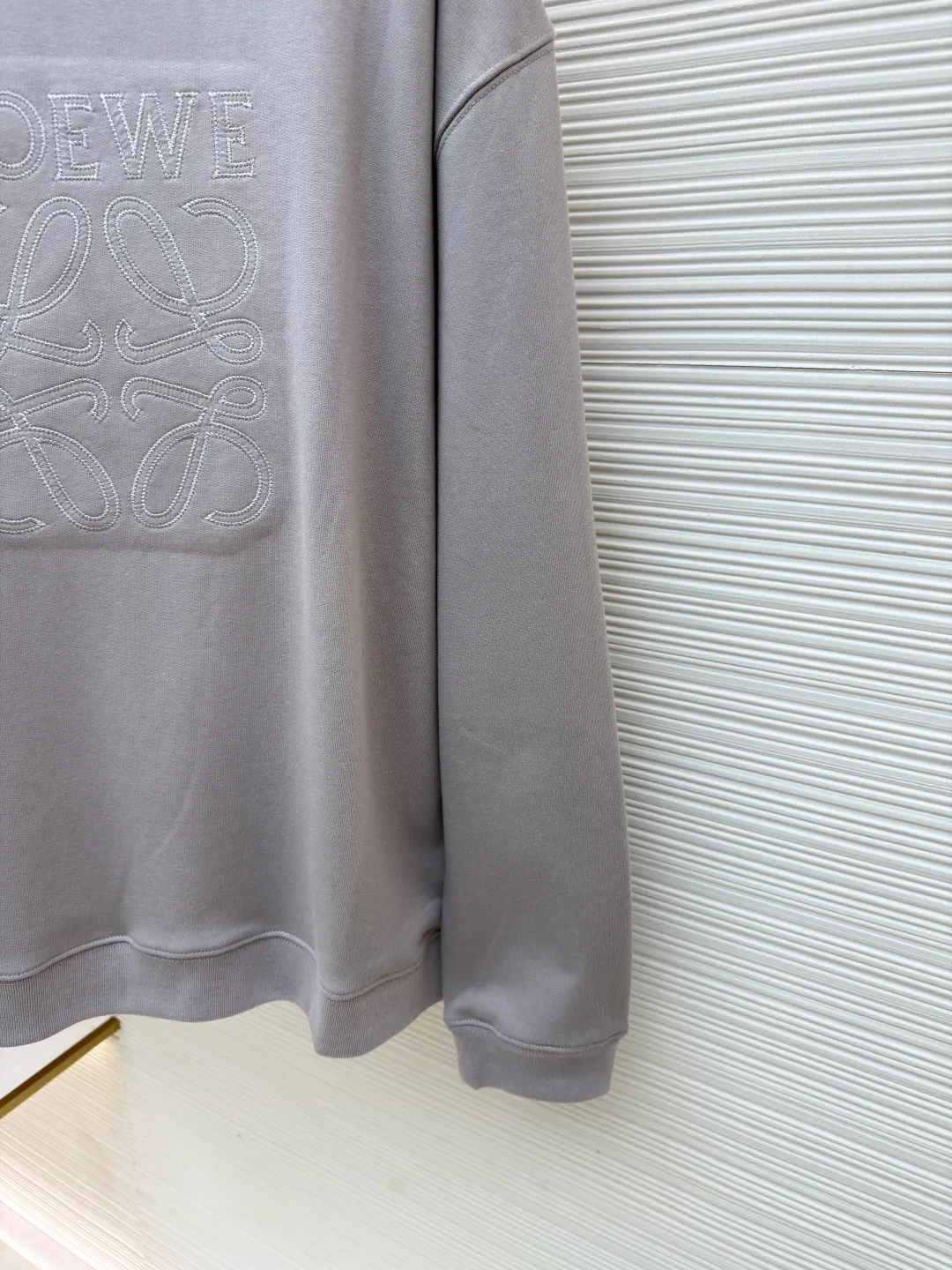 Loewe zigzag thread appliqué round neck sweatshirt ●Original version: Purchased and developed by 3621 ●Item number: 1680966-A90 ●Fabric: Fleece fabric ●Technology: Laser cutting appliqué production ●Version: Fitted version ●Weight: about 580g ●Size: 2*2 thread, 470g. The fish scale bottom fabric forms a fish scale pattern through a specific weaving process, and the plates are arranged and interwoven according to the warp and weft patterns and shapes to ensure clear texture and excellent texture. The fabric has been carefully produced and processed, and has good durability, lightness, softness, and good breathability. The edge-strengthened branches of the appliqué embroidery add a rough industrial look by imitating zigzag-shaped stitches. The appliqué stitches are in the form of trapezoidal zigzags, resembling interlaced canine teeth; emphasizing high stitch density and sharp turns, like saw blade cutting marks. Trim the seam allowance and cut off excess fabric along the dogtooth stitches to retain the jagged three-dimensional effect. After the garment is made, it is made through frying process. The garment is dyed, washed and aged using new environmentally friendly technology. Fabrics are dyed using a stone grinding method, and the garments are continuously immersed in dye and tumbled. After frying the sand, the fabric fades slightly, changing the color of the original fabric to show a nostalgic color with different shades of light and dark. The neckline adopts a structural feature formed by a V-shaped rib weaving method, which visually has a unique sense of line and extensibility. The rib structure itself has good elasticity and stretchability; inserts are added to the shoulder seams to increase the service life. The neckline, hem, and cuffs are all spliced ​​with double-needle threading. The body and sleeves are structurally split and quilted. The fabric material has high ductility and no sense of restraint. The overall wiring is straight and delicate, the fabric is comfortable and soft, and the color is consistent without color difference. It can be matched with the same style to create a fashionable look and control various occasions. Customized accessories, complete with three standards, same style for men and women!