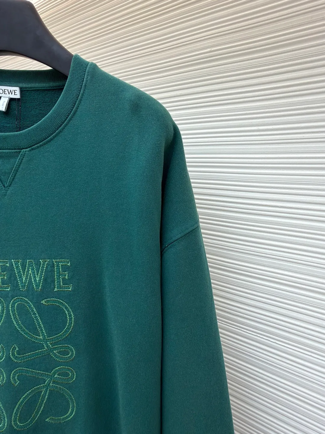 Loewe zigzag thread appliqué round neck sweatshirt ●Original version: Purchased and developed by 3621 ●Item number: 1680967-A90 ●Fabric: Fleece fabric ●Technology: Laser cutting appliqué production ●Version: Fitted version ●Weight: about 635g ●Size: 2*2 thread, 470g. The fish scale bottom fabric forms a fish scale pattern through a specific weaving process, and the plates are arranged and interwoven according to the warp and weft patterns and shapes to ensure clear texture and excellent texture. The fabric has been carefully produced and processed, and has good durability, lightness, softness, and good breathability. The edge-strengthened branches of the appliqué embroidery add a rough industrial look by imitating zigzag-shaped stitches. The appliqué stitches are in the form of trapezoidal zigzags, resembling interlaced canine teeth; emphasizing high stitch density and sharp turns, like saw blade cutting marks. Trim the seam allowance and cut off excess fabric along the dogtooth stitches to retain the jagged three-dimensional effect. After the garment is made, it is made through frying process. The garment is dyed, washed and aged using new environmentally friendly technology. Fabrics are dyed using a stone grinding method, and the garments are continuously immersed in dye and tumbled. After frying the sand, the fabric fades slightly, changing the color of the original fabric to show a nostalgic color with different shades of light and dark. The neckline adopts a structural feature formed by a V-shaped rib weaving method, which visually has a unique sense of line and extensibility. The rib structure itself has good elasticity and stretchability; inserts are added to the shoulder seams to increase the service life. The neckline, hem, and cuffs are all spliced ​​with double-needle threading. The body and sleeves are structurally split and quilted. The fabric material has high ductility and no sense of restraint. The overall wiring is straight and delicate, the fabric is comfortable and soft, and the color is consistent without color difference. It can be matched with the same style to create a fashionable look and control various occasions. Customized accessories, complete with three standards, same style for men and women!