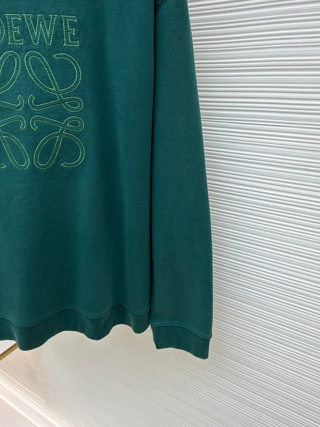 Loewe zigzag thread appliqué round neck sweatshirt ●Original version: Purchased and developed by 3621 ●Item number: 1680967-A90 ●Fabric: Fleece fabric ●Technology: Laser cutting appliqué production ●Version: Fitted version ●Weight: about 635g ●Size: 2*2 thread, 470g. The fish scale bottom fabric forms a fish scale pattern through a specific weaving process, and the plates are arranged and interwoven according to the warp and weft patterns and shapes to ensure clear texture and excellent texture. The fabric has been carefully produced and processed, and has good durability, lightness, softness, and good breathability. The edge-strengthened branches of the appliqué embroidery add a rough industrial look by imitating zigzag-shaped stitches. The appliqué stitches are in the form of trapezoidal zigzags, resembling interlaced canine teeth; emphasizing high stitch density and sharp turns, like saw blade cutting marks. Trim the seam allowance and cut off excess fabric along the dogtooth stitches to retain the jagged three-dimensional effect. After the garment is made, it is made through frying process. The garment is dyed, washed and aged using new environmentally friendly technology. Fabrics are dyed using a stone grinding method, and the garments are continuously immersed in dye and tumbled. After frying the sand, the fabric fades slightly, changing the color of the original fabric to show a nostalgic color with different shades of light and dark. The neckline adopts a structural feature formed by a V-shaped rib weaving method, which visually has a unique sense of line and extensibility. The rib structure itself has good elasticity and stretchability; inserts are added to the shoulder seams to increase the service life. The neckline, hem, and cuffs are all spliced ​​with double-needle threading. The body and sleeves are structurally split and quilted. The fabric material has high ductility and no sense of restraint. The overall wiring is straight and delicate, the fabric is comfortable and soft, and the color is consistent without color difference. It can be matched with the same style to create a fashionable look and control various occasions. Customized accessories, complete with three standards, same style for men and women!